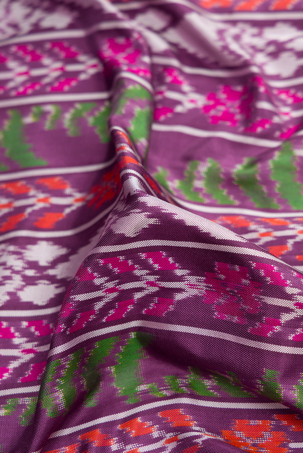 Close up of Purple Dual Tone Double Ikat Saree with Ikat Print on the body and Plain Border.  displaying folds