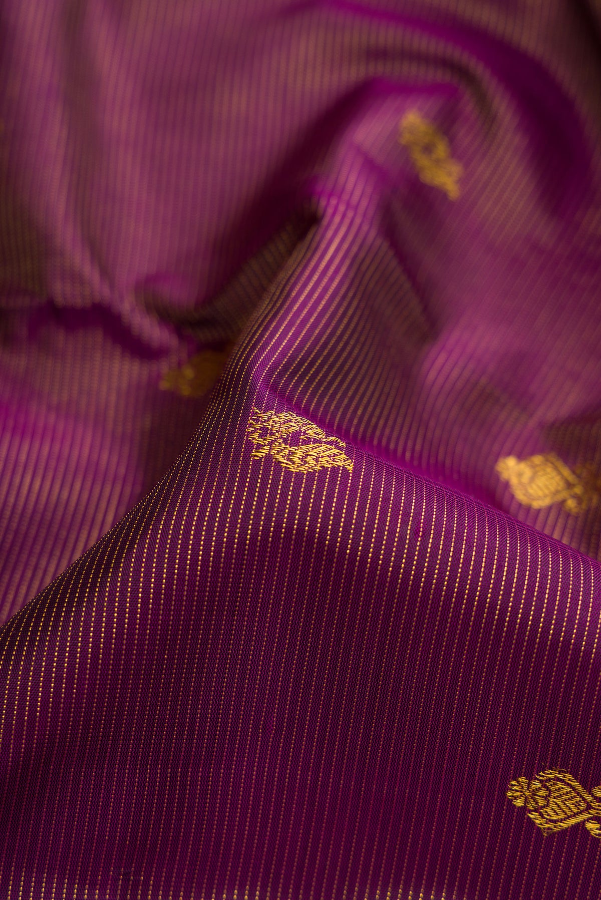 Close up of Pure Silk Pure Zari Burgundy Dual Tone Kanjivaram Saree with Stripes on the body and Zari Border.  displaying folds