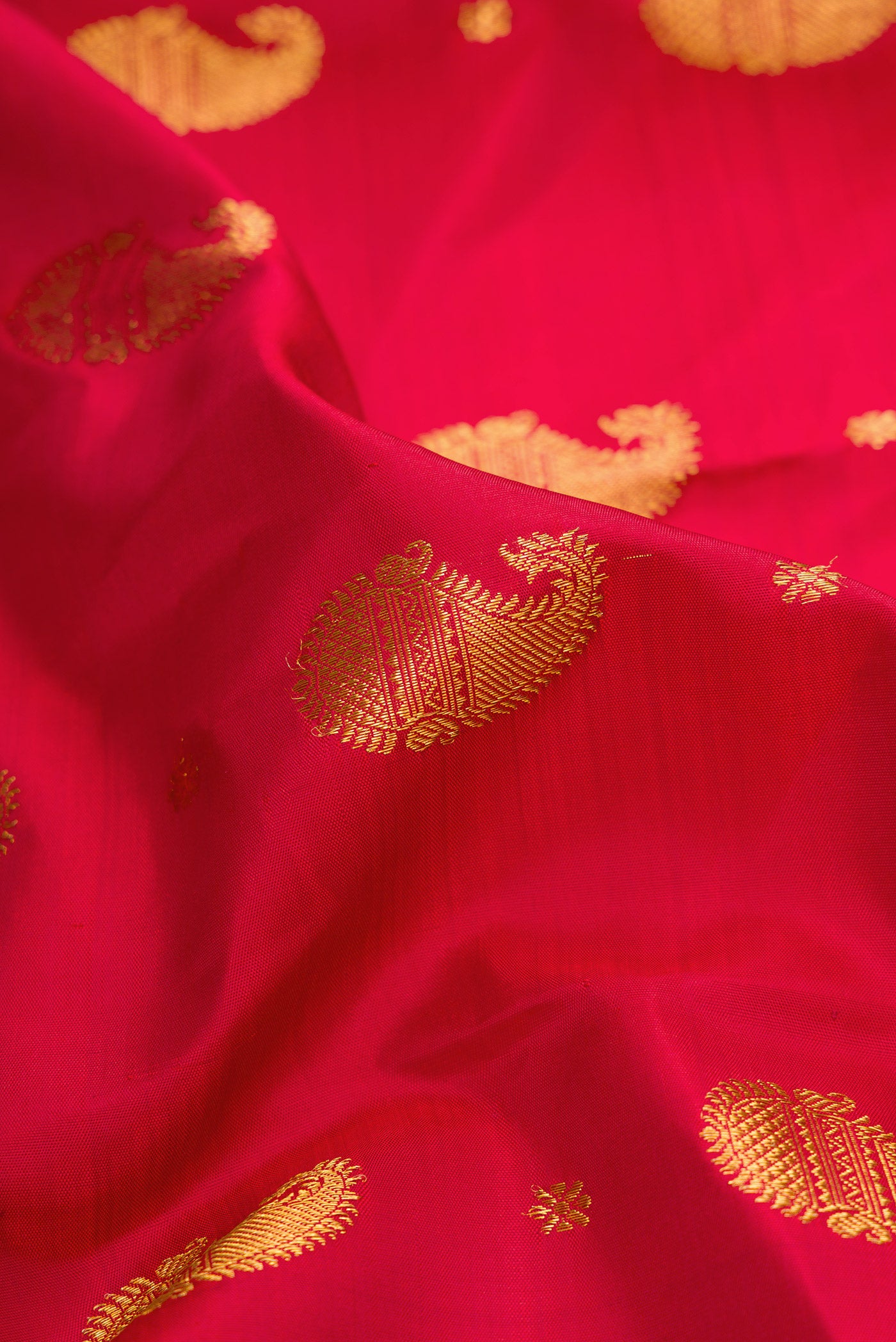 Close up of Pure Silk Pure Zari Red Dual Tone Kanjivaram Saree with Zari Butta on the body and Zari Border.  displaying folds