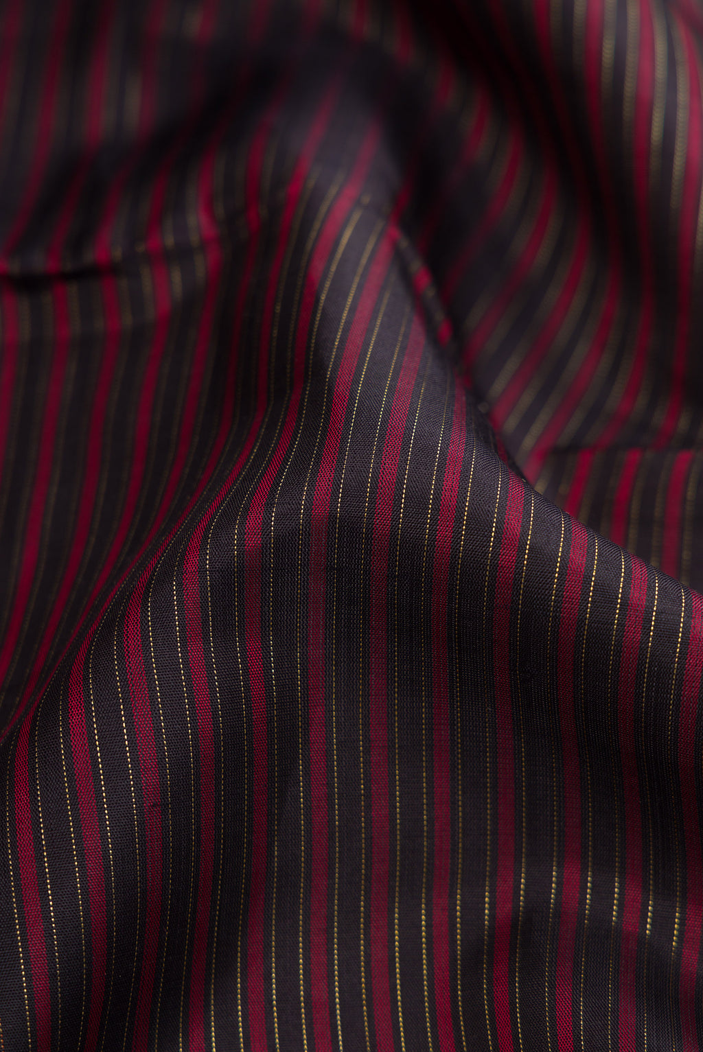 Close up of Pure Silk Pure Zari Burgundy Dual Tone Kanchipuram Saree with Stripes on the body and Zari Border.  displaying folds