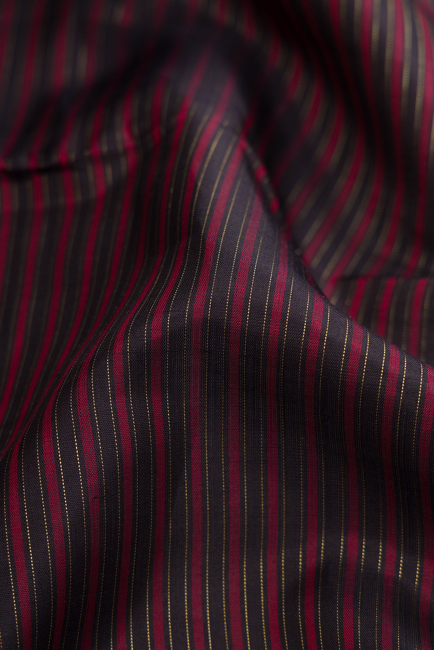 Close up of Pure Silk Pure Zari Burgundy Dual Tone Kanchipuram Saree with Stripes on the body and Zari Border.  displaying folds