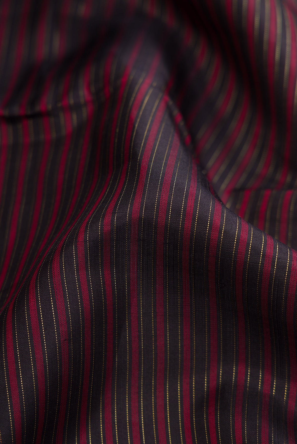 Close up of Pure Silk Pure Zari Burgundy Dual Tone Kanchipuram Saree with Stripes on the body and Zari Border.  displaying folds