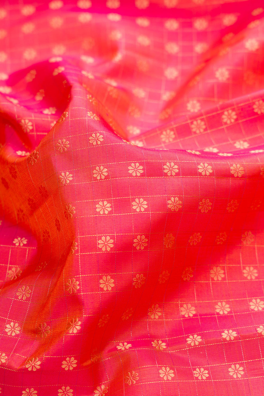 Close up of Pure Silk Pure Zari Coral Dual Tone Kanchipuram Saree with Zari Butta on the body and Zari Border.  displaying folds