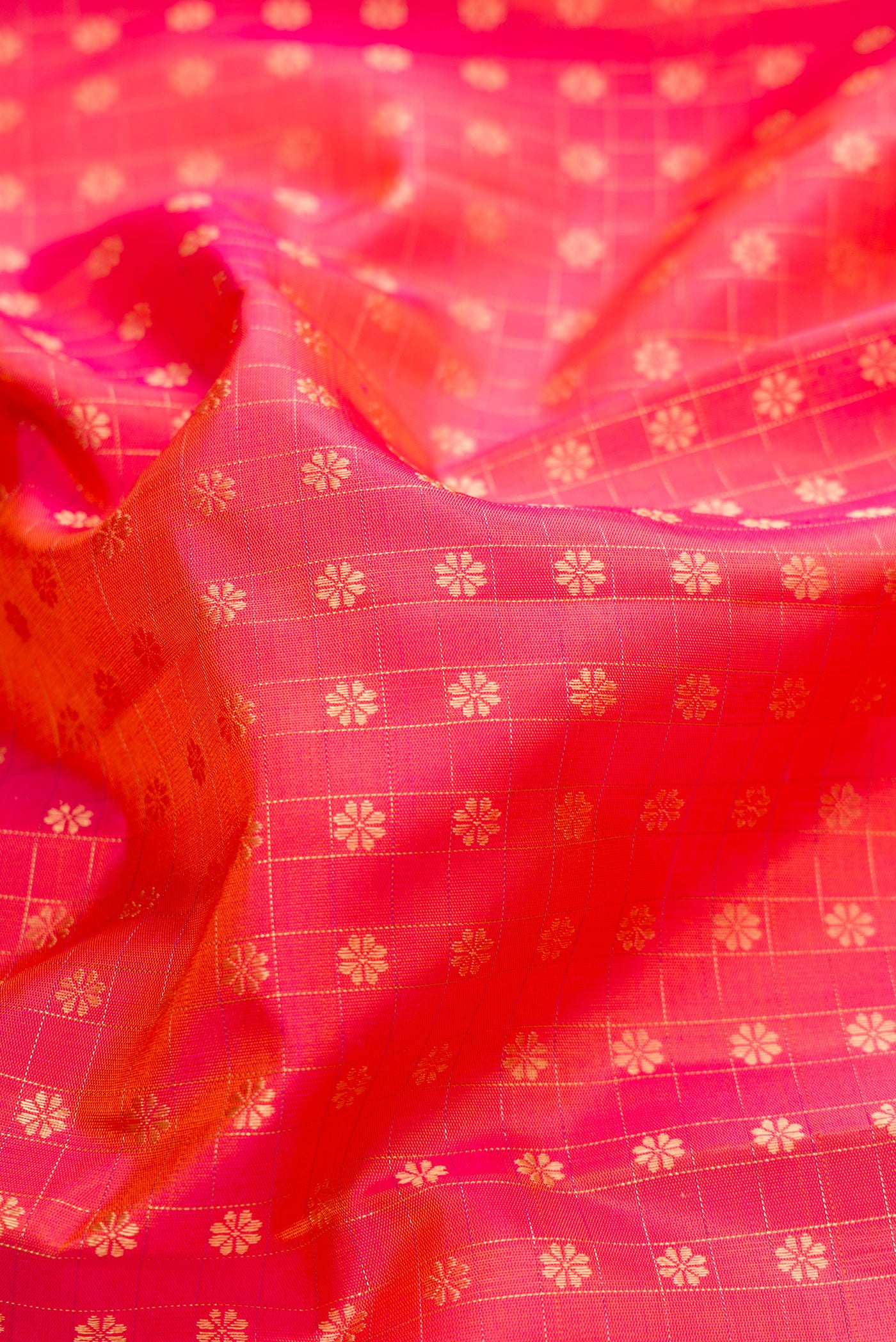 Close up of Pure Silk Pure Zari Coral Dual Tone Kanchipuram Saree with Zari Butta on the body and Zari Border.  displaying folds
