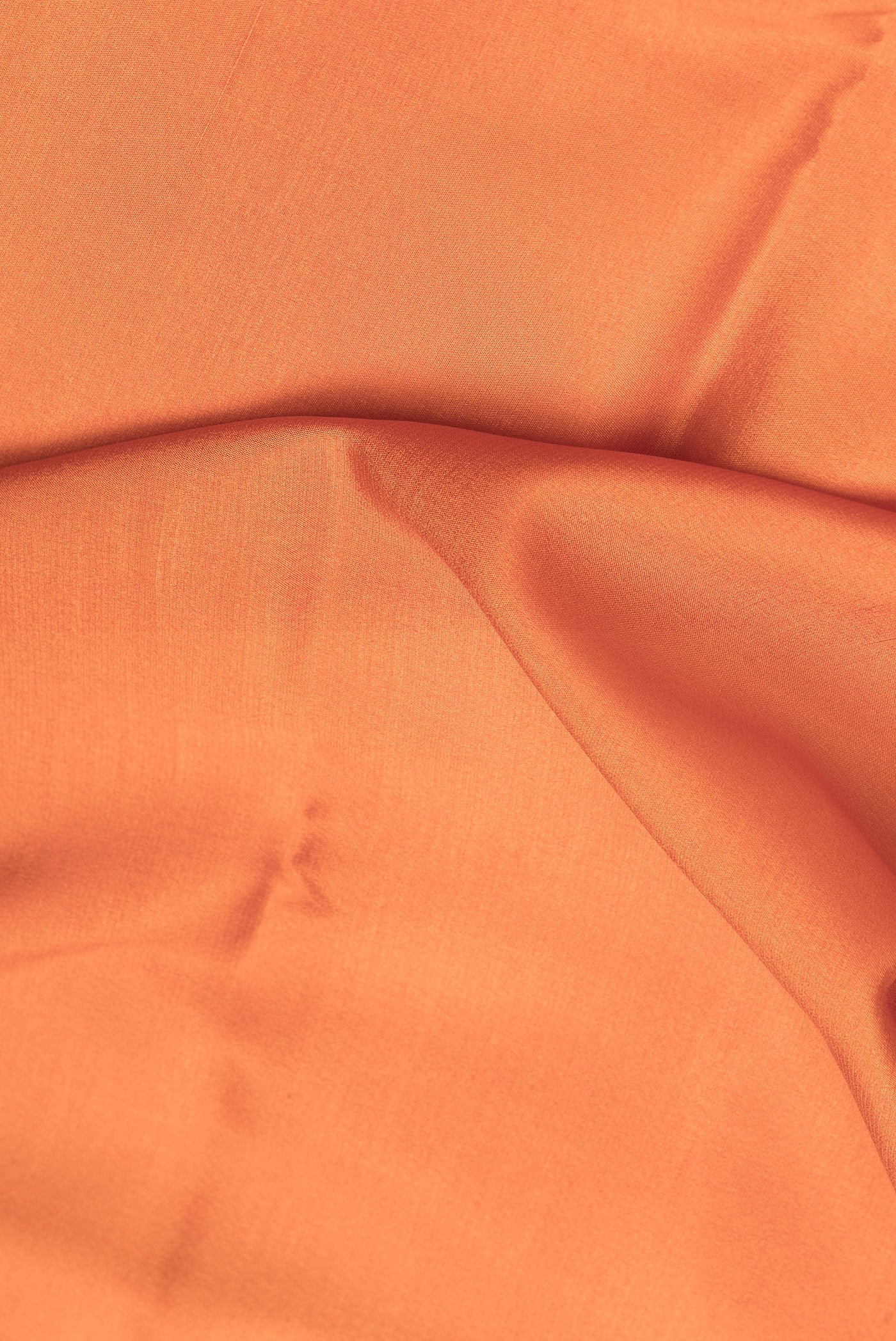 Close up of Brick Orange Mysore Crepe Saree with Plain Body and Zari Border.  displaying folds
