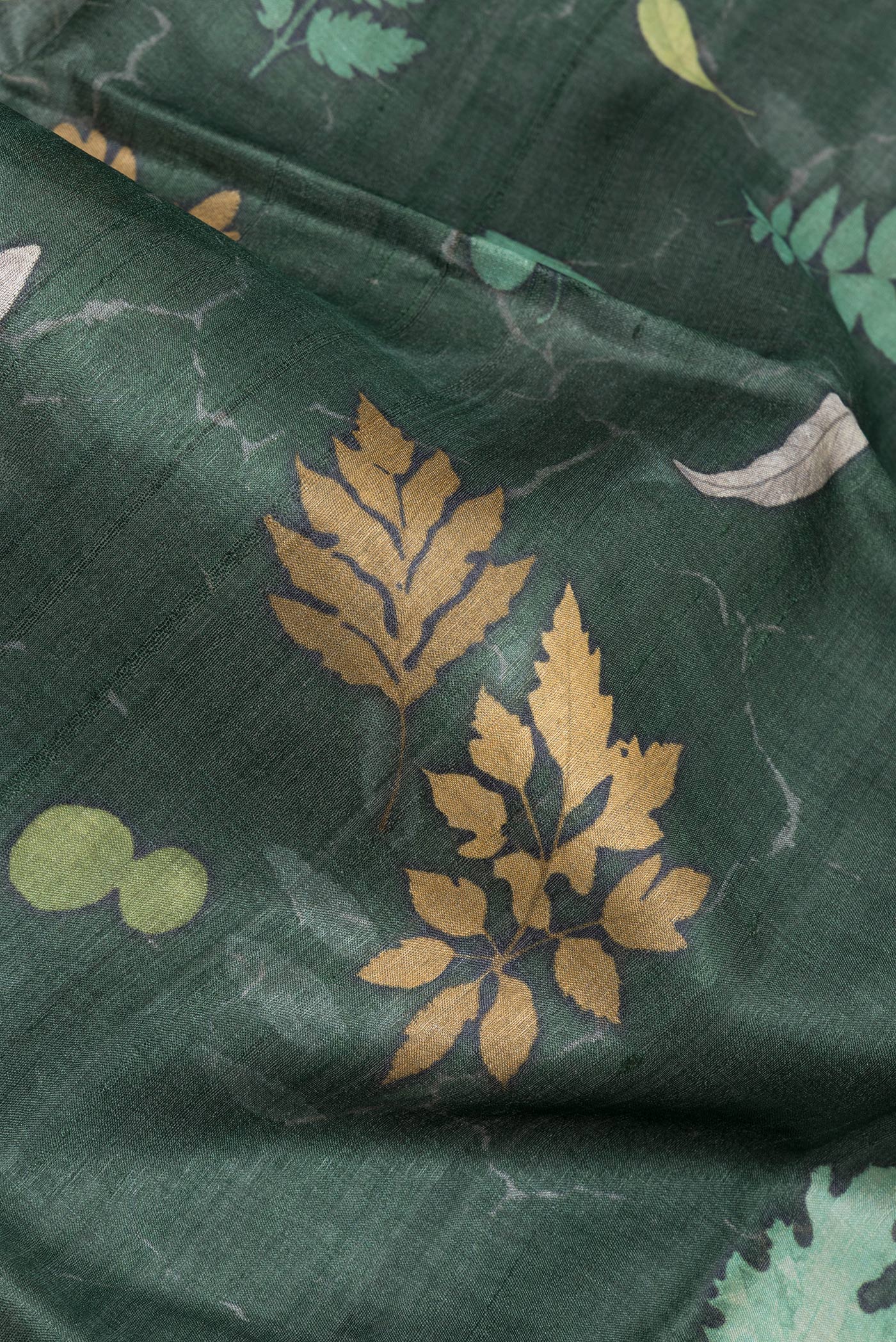 Close up of Bottle Green Tussar Silk Saree with Floral Print on the body and Zari Border.  displaying folds