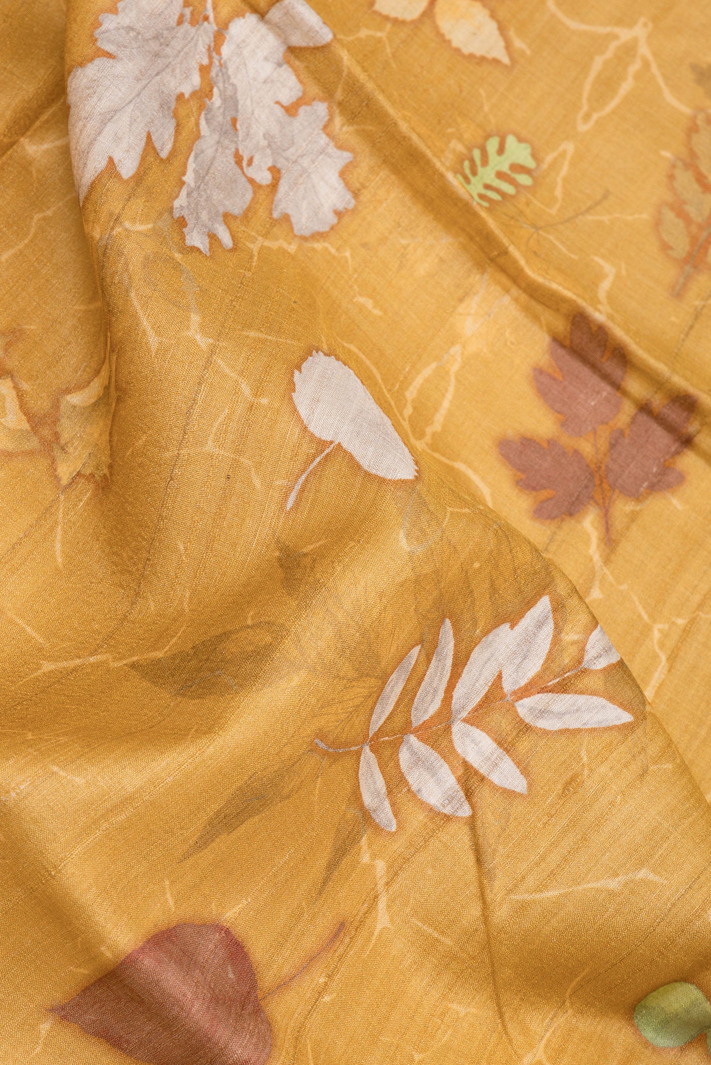 Close up of Mustard Tussar Silk Saree with Printed design on the body and Zari Border.  displaying folds