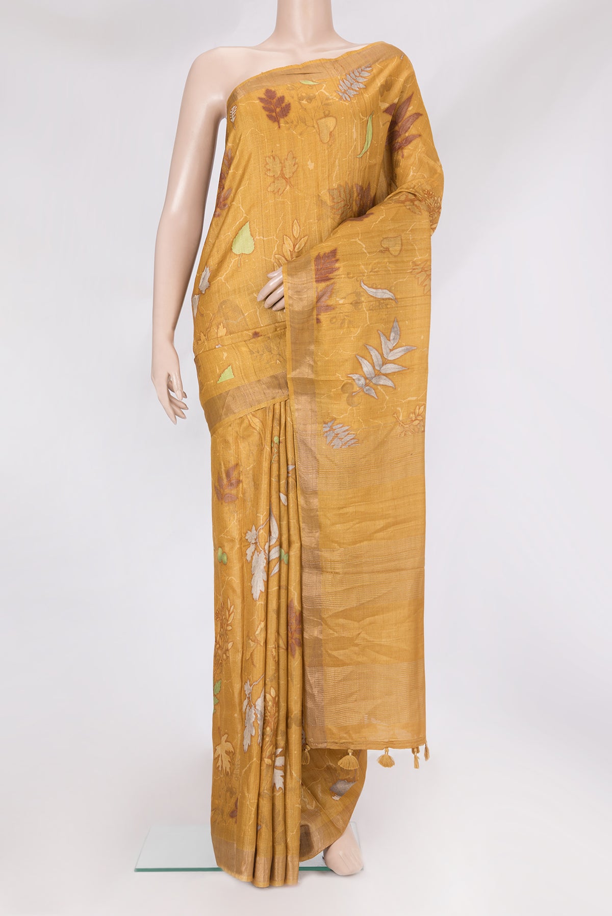 Mustard Tussar Silk Saree with Printed design on the body and Zari Border.  displayed on a mannequin