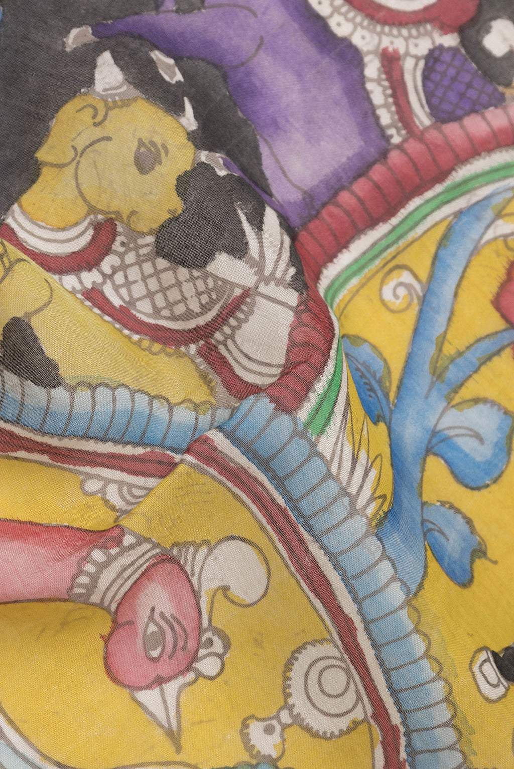 Close up of Yellow Tussar Silk Saree with kalamkari Print on the body and Zari Border.  displaying folds