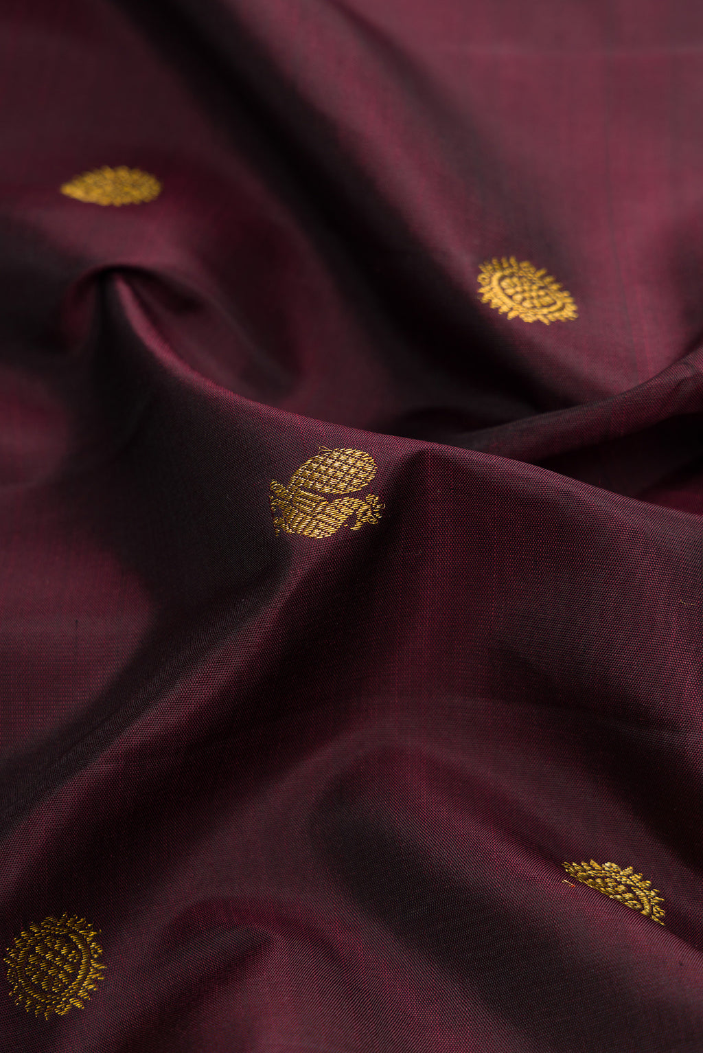 Close up of Burgundy Dual Tone Kanjivaram Silk Saree with Zari Butta on the body and Zari Border.  displaying folds