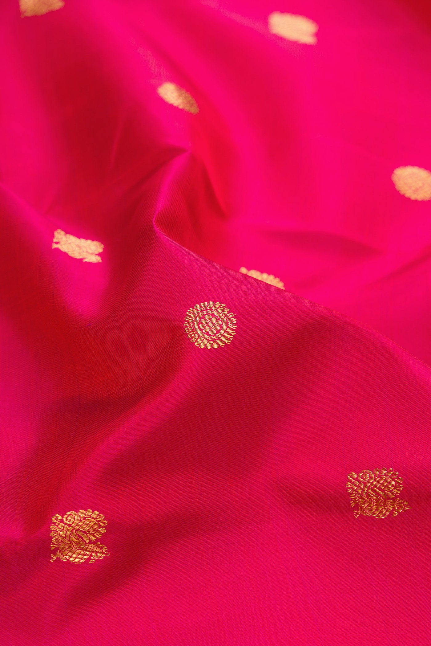 Close up of Dark Pink Kanjivaram Silk Saree with Zari Butta on the body and Zari Border.  displaying folds