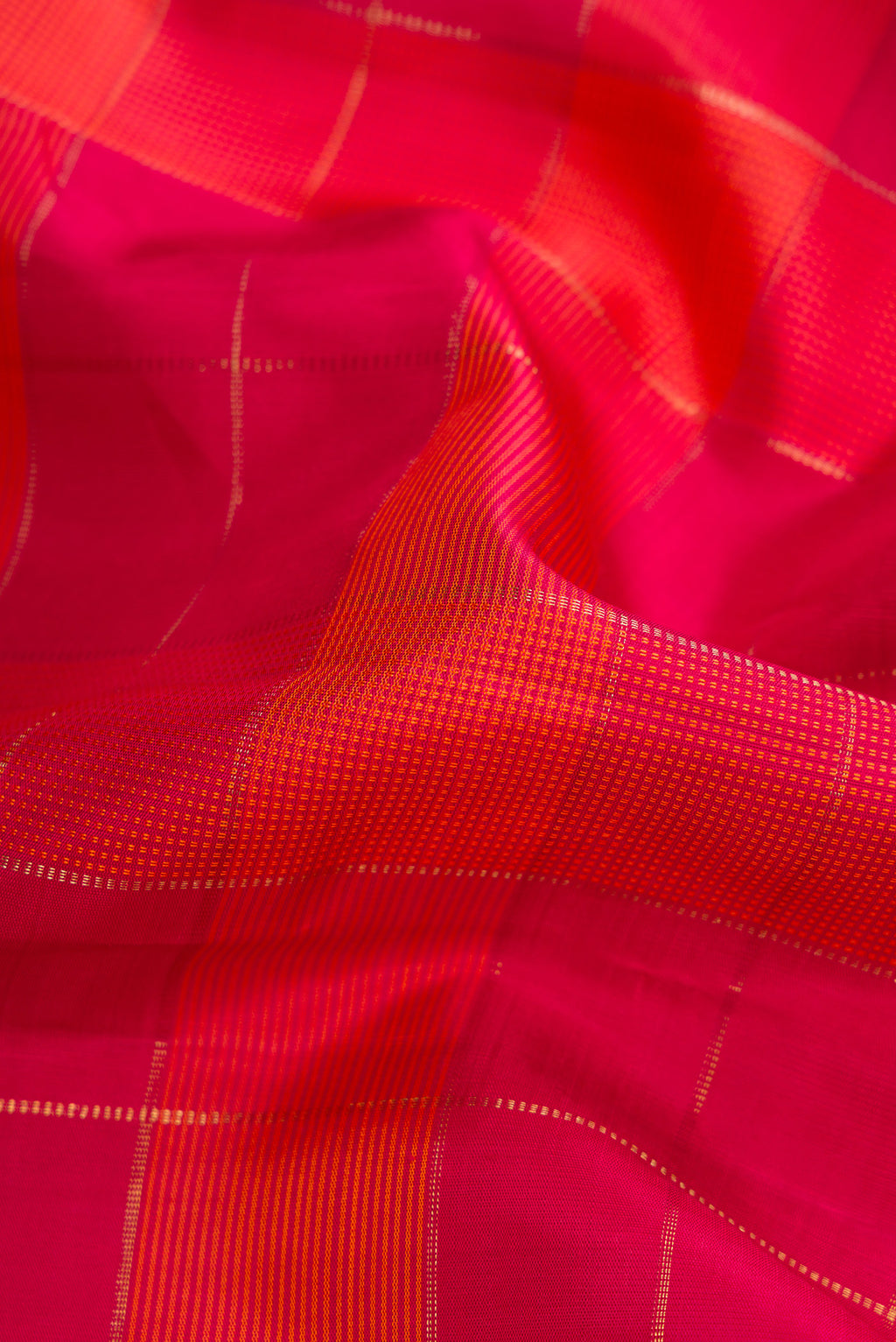 Close up of Pure Silk Pure Zari Dark Pink and Brick Orange Color Kanchipuram Saree with Checked design on the body and Thread Border.  displaying folds