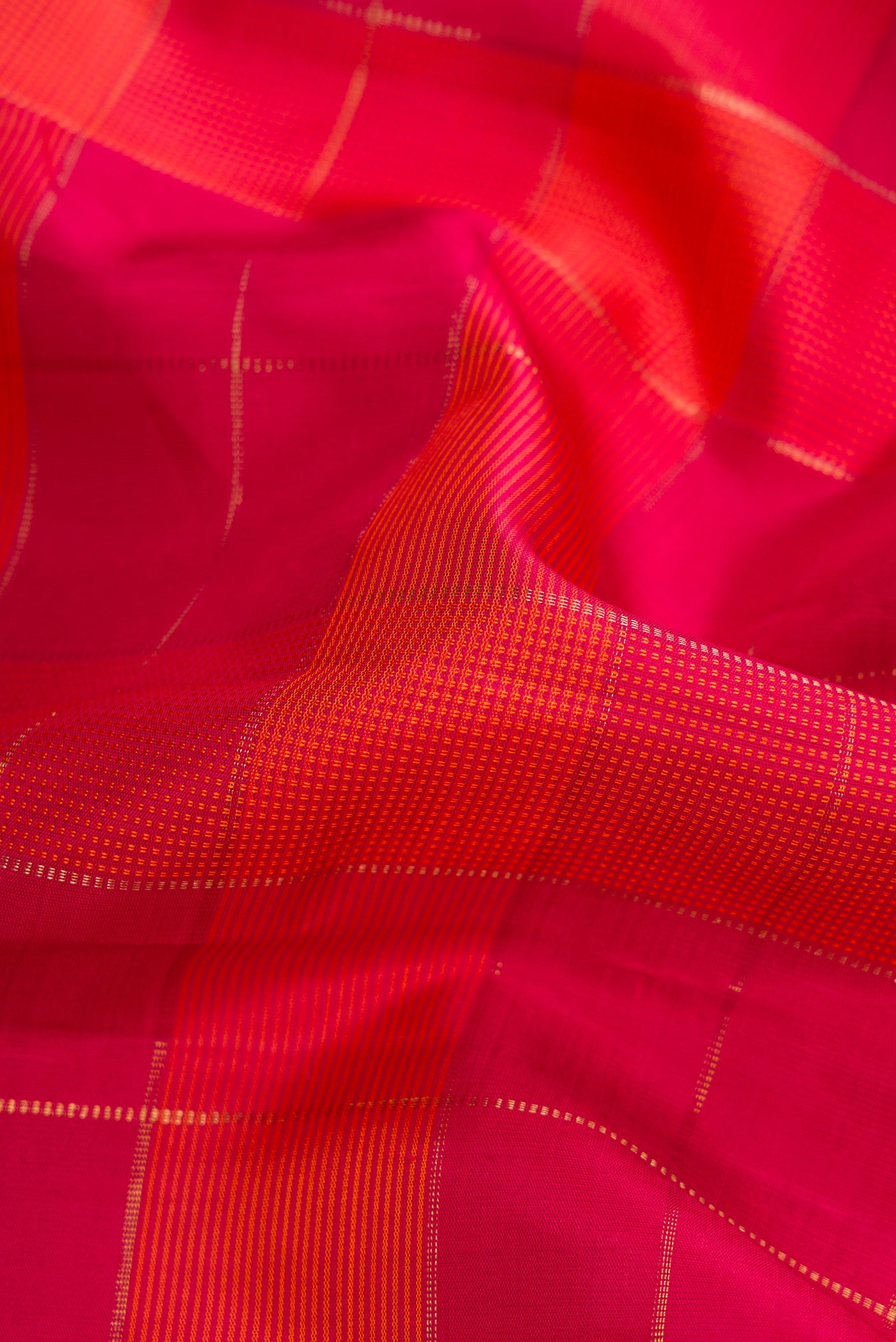 Close up of Pure Silk Pure Zari Dark Pink and Brick Orange Color Kanchipuram Saree with Checked design on the body and Thread Border.  displaying folds
