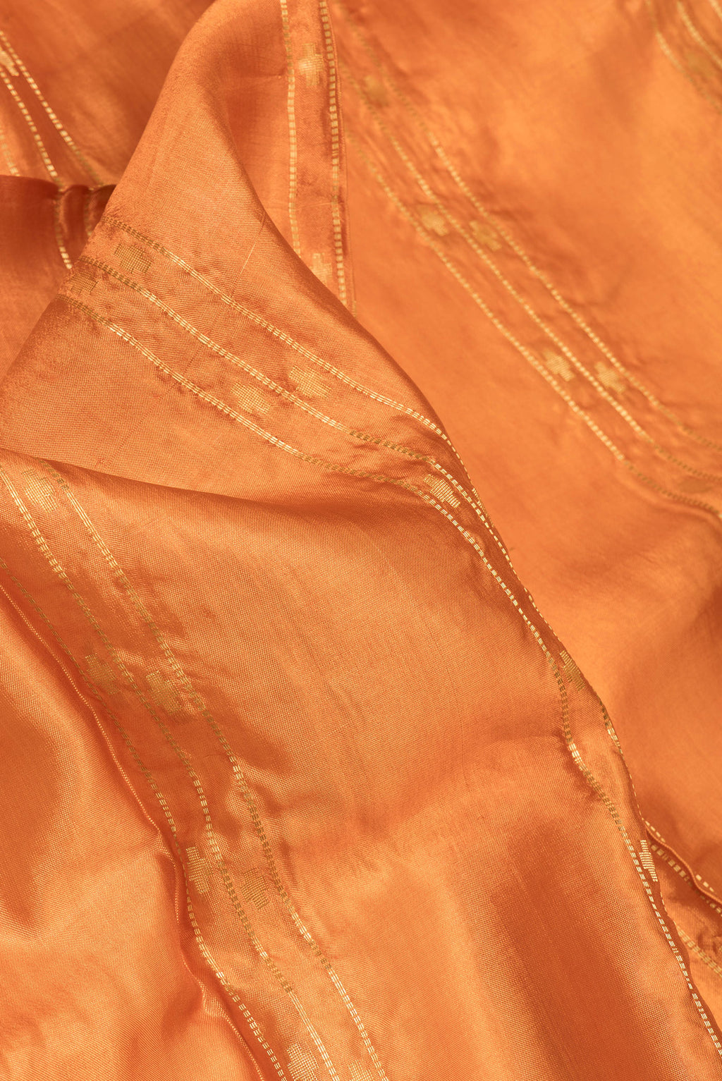 Close up of Orange Dual Tone Blended Tussar Silk Saree with Printed design on the body and Zari Border.  displaying folds
