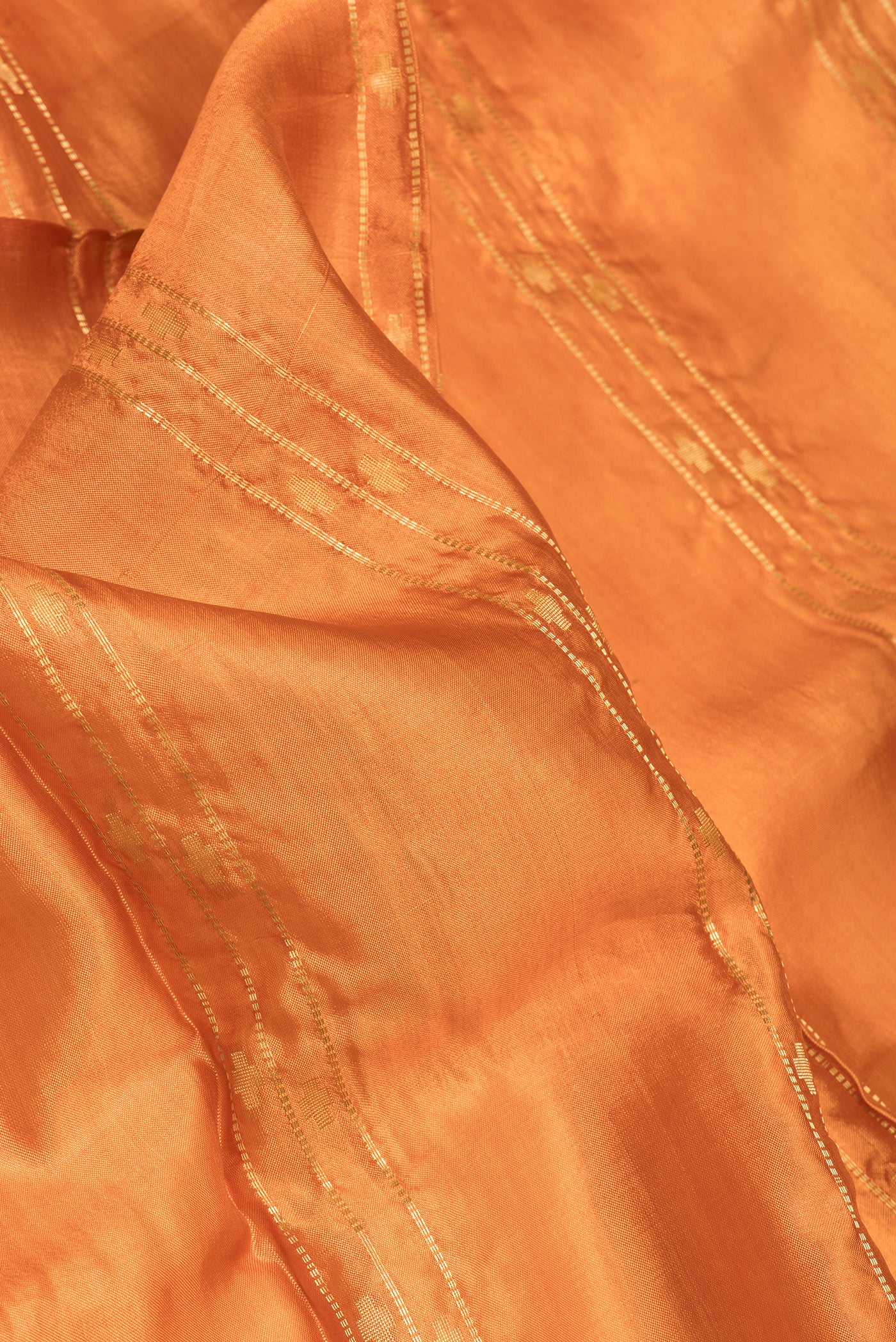 Close up of Orange Dual Tone Blended Tussar Silk Saree with Printed design on the body and Zari Border.  displaying folds