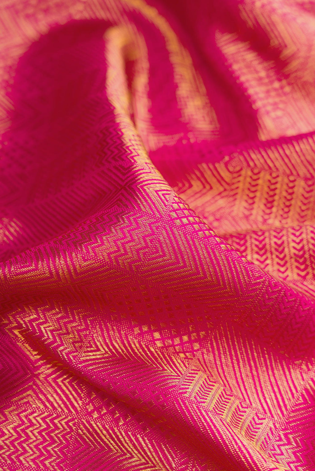 Close up of Dark Pink Kanchipuram Silk Saree with Zari Brocade on the body and Zari Border.  displaying folds