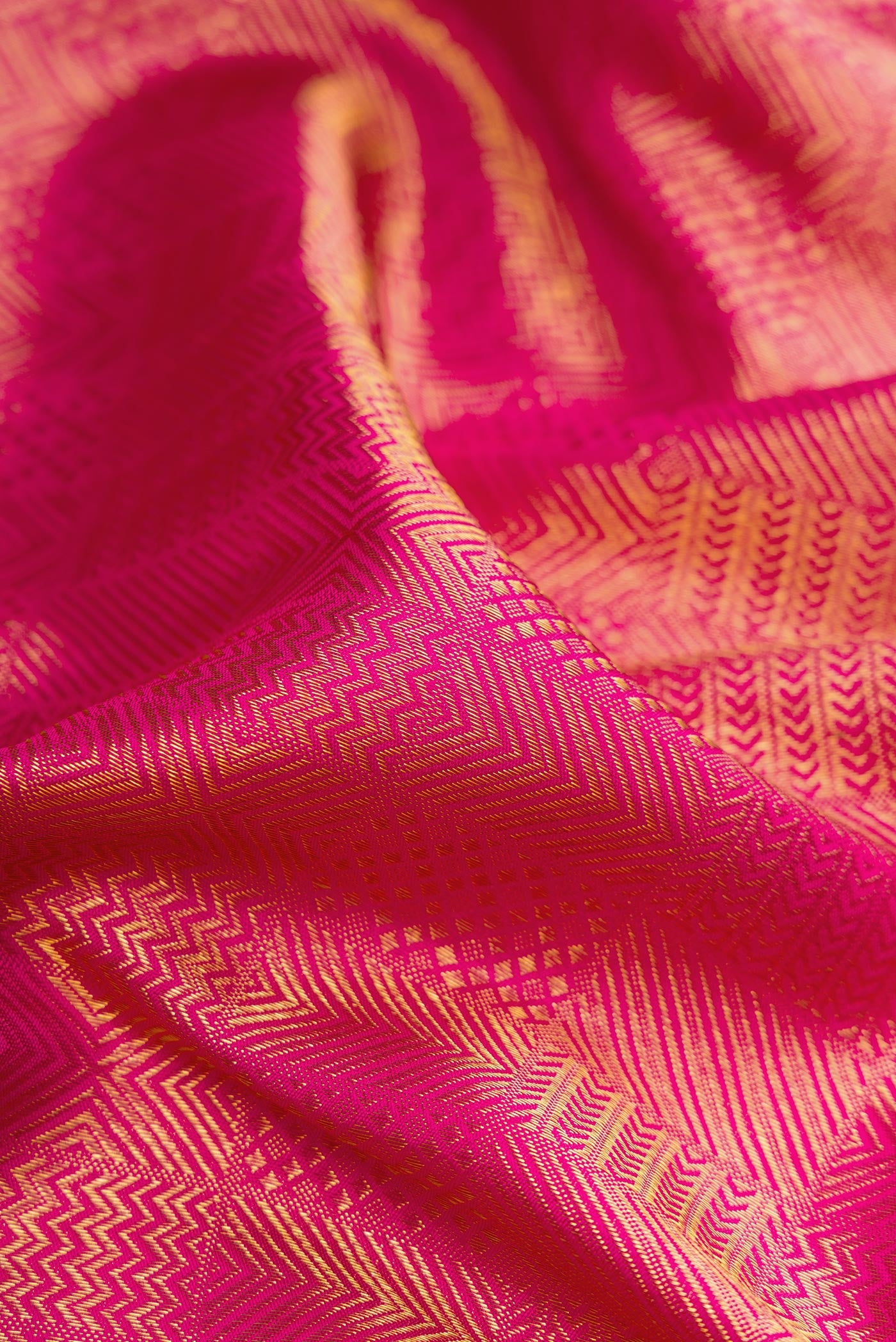 Close up of Dark Pink Kanchipuram Silk Saree with Zari Brocade on the body and Zari Border.  displaying folds