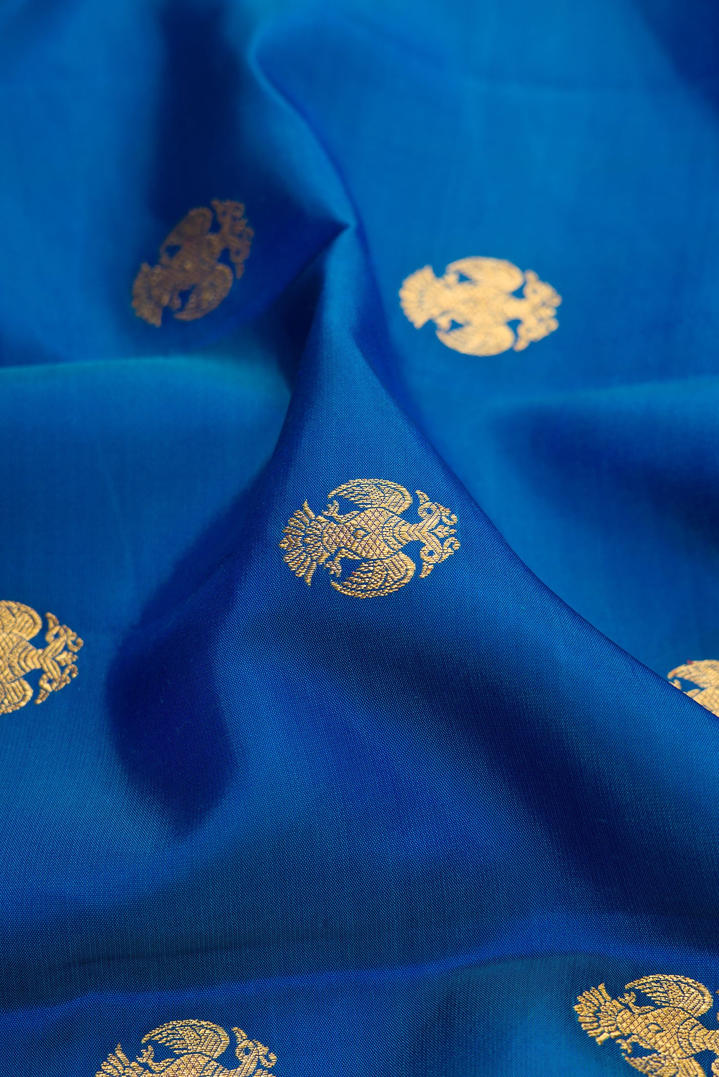 Close up of Peacock Blue Kanchipuram Silk Saree with Zari Butta on the body and Zari Border.  displaying folds