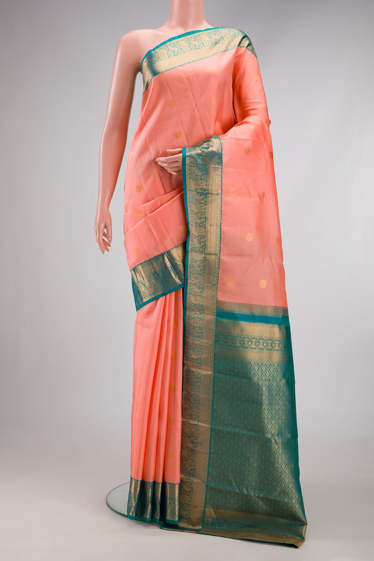 Peach Kanchipuram Silk Saree with Zari Butta on the body and Zari Border.  displayed on a mannequin