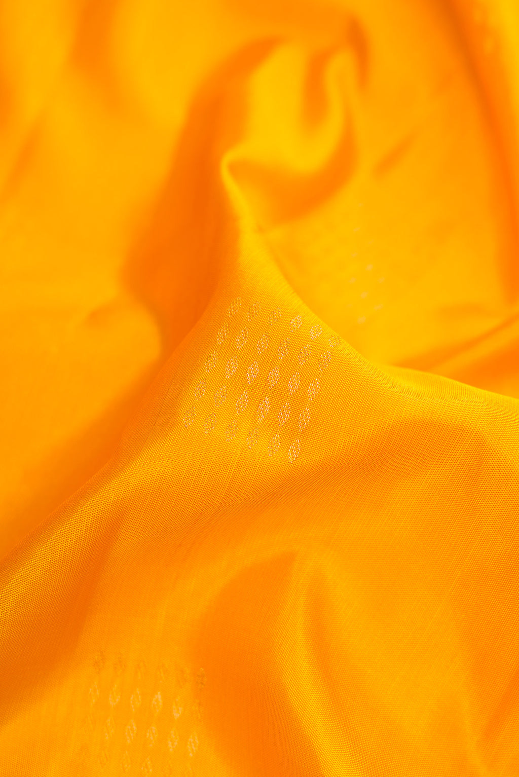 Close up of Mustard Dual Tone Soft Silk Saree with Zari Butta on the body and Zari Border.  displaying folds