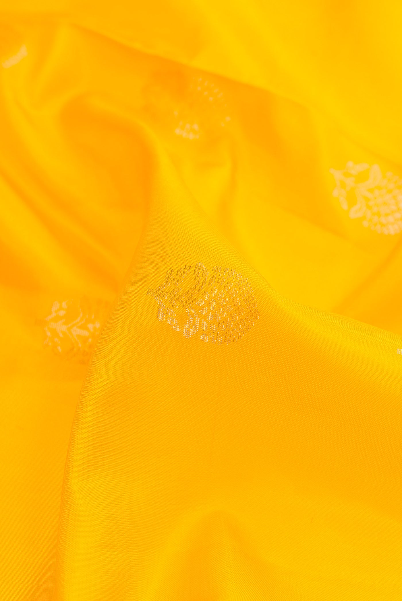 Close up of Yellow Dual Tone Soft Silk Saree with Zari Butta on the body and Zari Border.  displaying folds