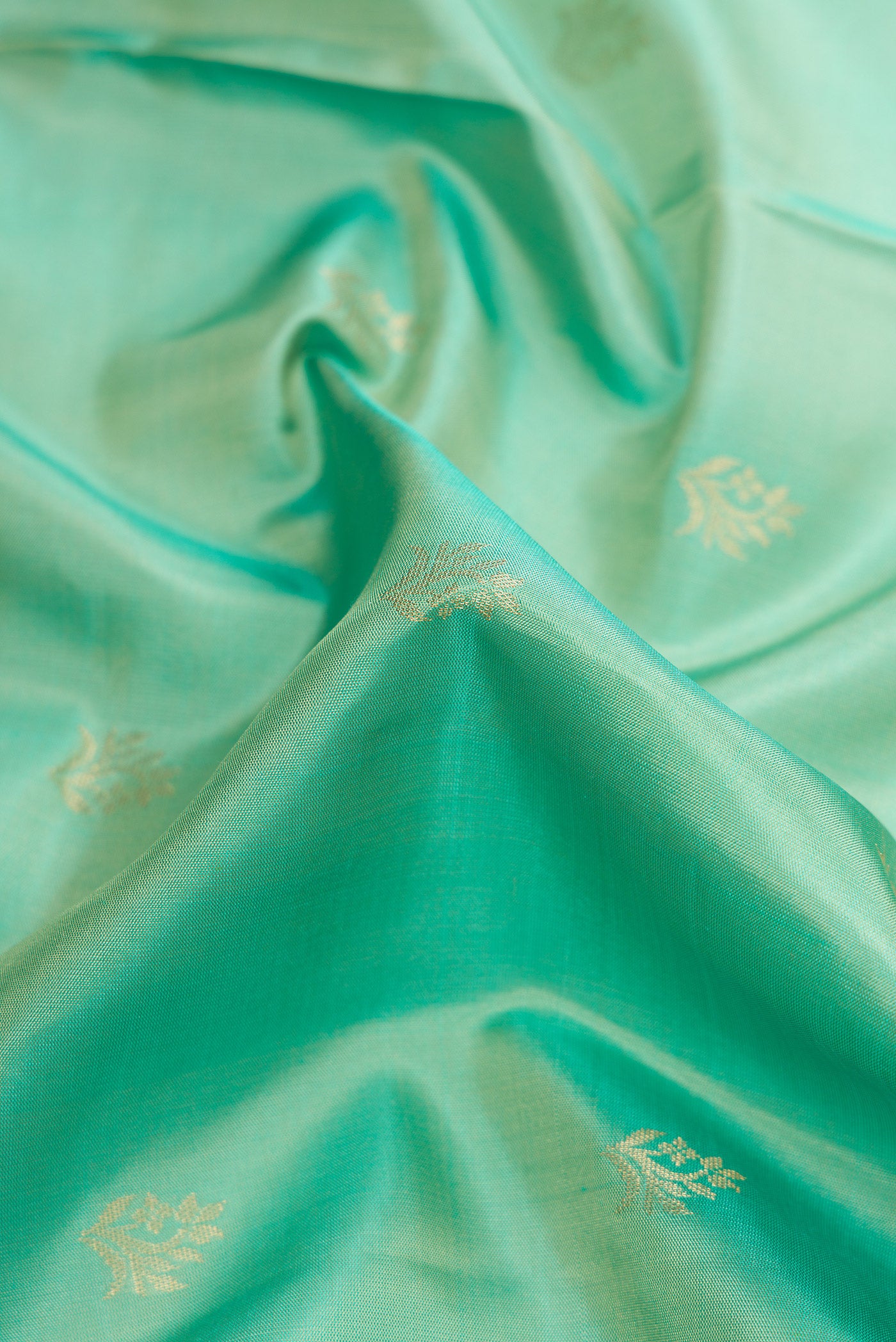 Close up of Pista Green Dual Tone Soft Silk Saree with Zari Butta on the body and Zari Border.  displaying folds