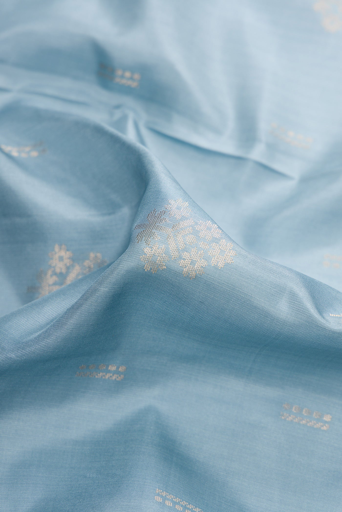 Close up of Light Blue Dual Tone Soft Silk Saree with Zari Butta on the body and Zari Border.  displaying folds