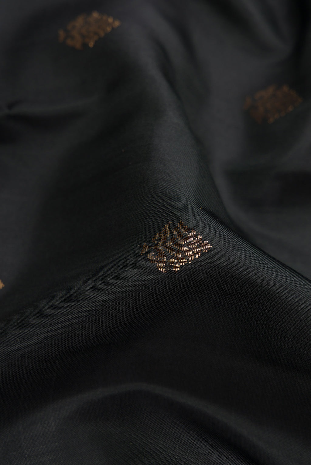 Close up of Black Dual Tone Soft Silk Saree with Zari Butta on the body and Zari Border.  displaying folds
