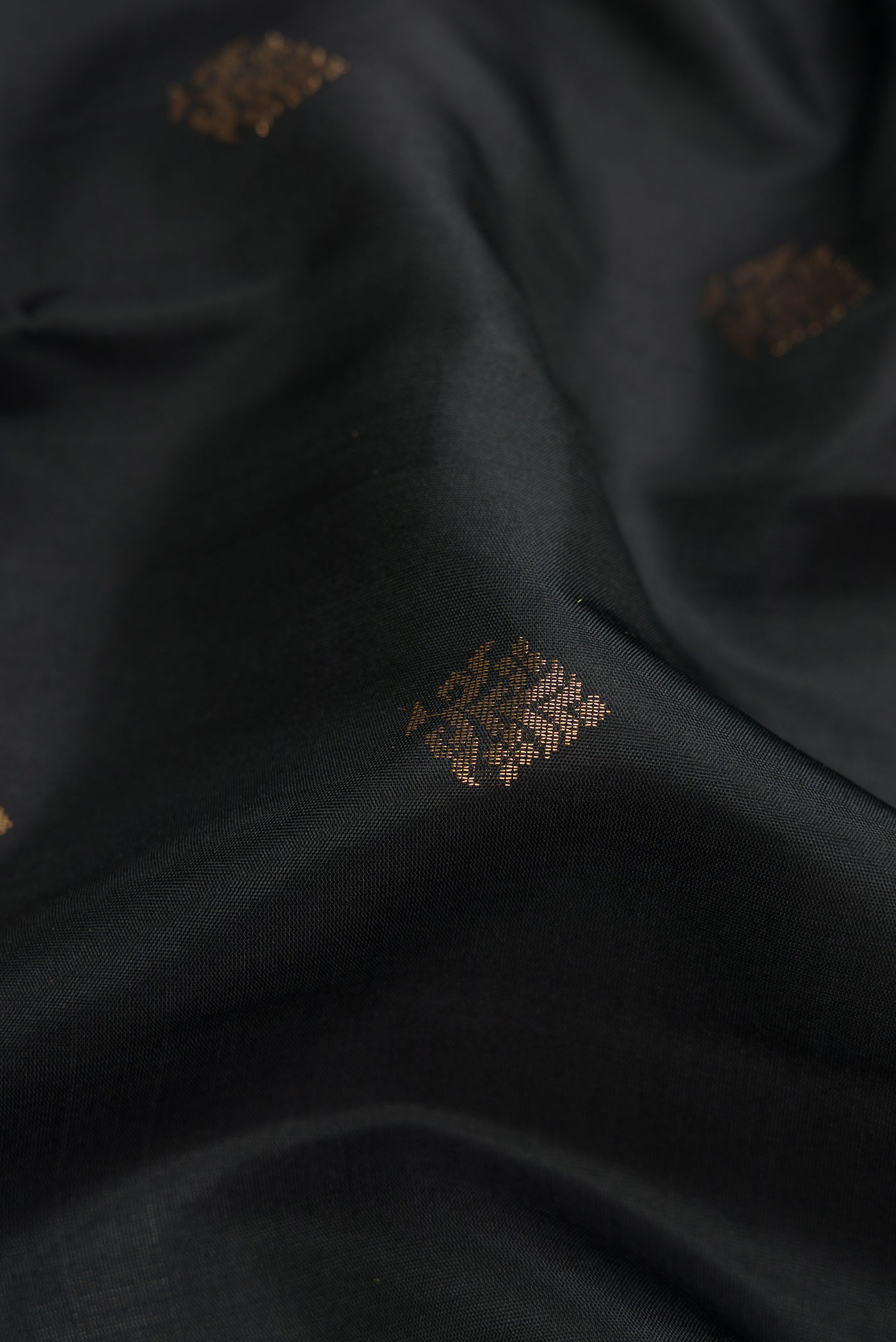 Close up of Black Dual Tone Soft Silk Saree with Zari Butta on the body and Zari Border.  displaying folds