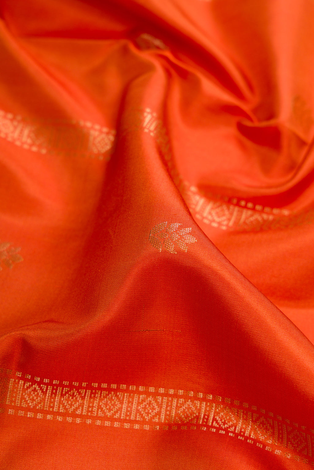 Close up of Brick Orange Dual Tone Soft Silk Saree with Stripes on the body and Zari Border.  displaying folds