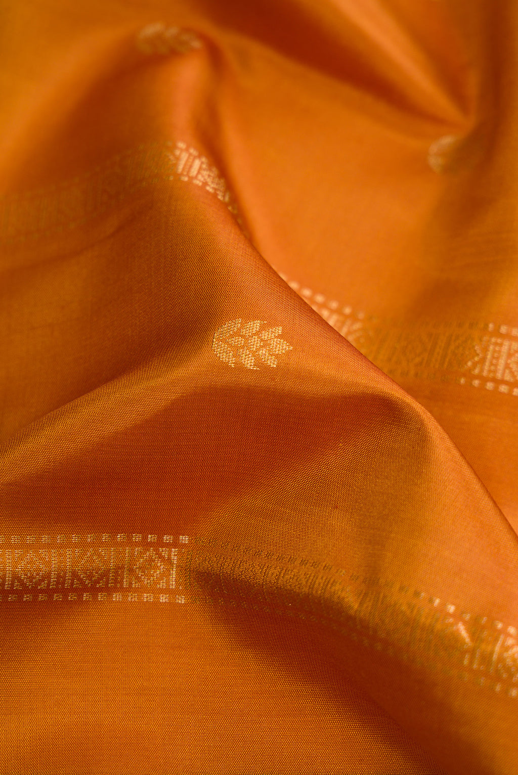 Close up of Mustard Dual Tone Soft Silk Saree with Zari Butta on the body and Zari Border.  displaying folds