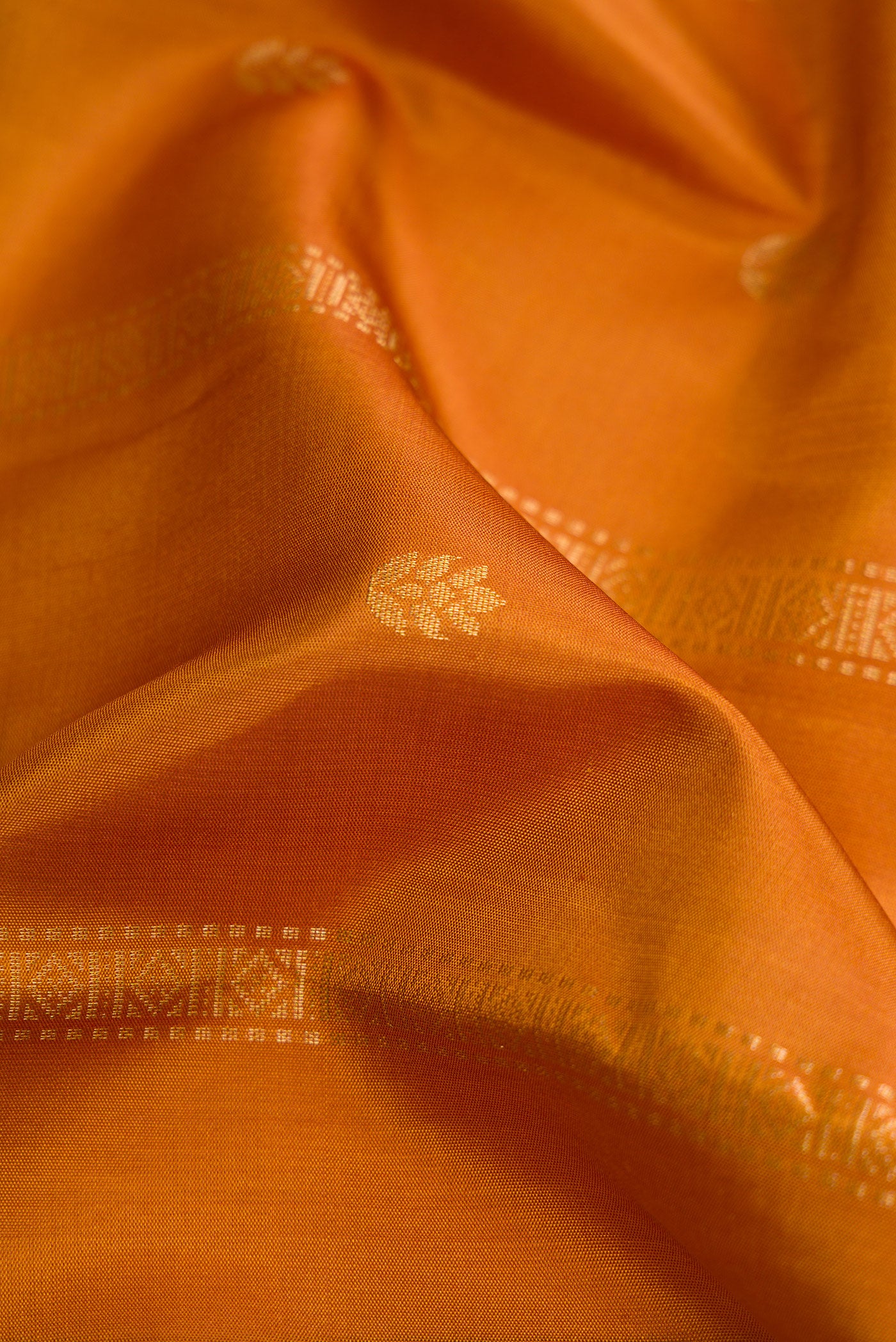 Close up of Mustard Dual Tone Soft Silk Saree with Zari Butta on the body and Zari Border.  displaying folds