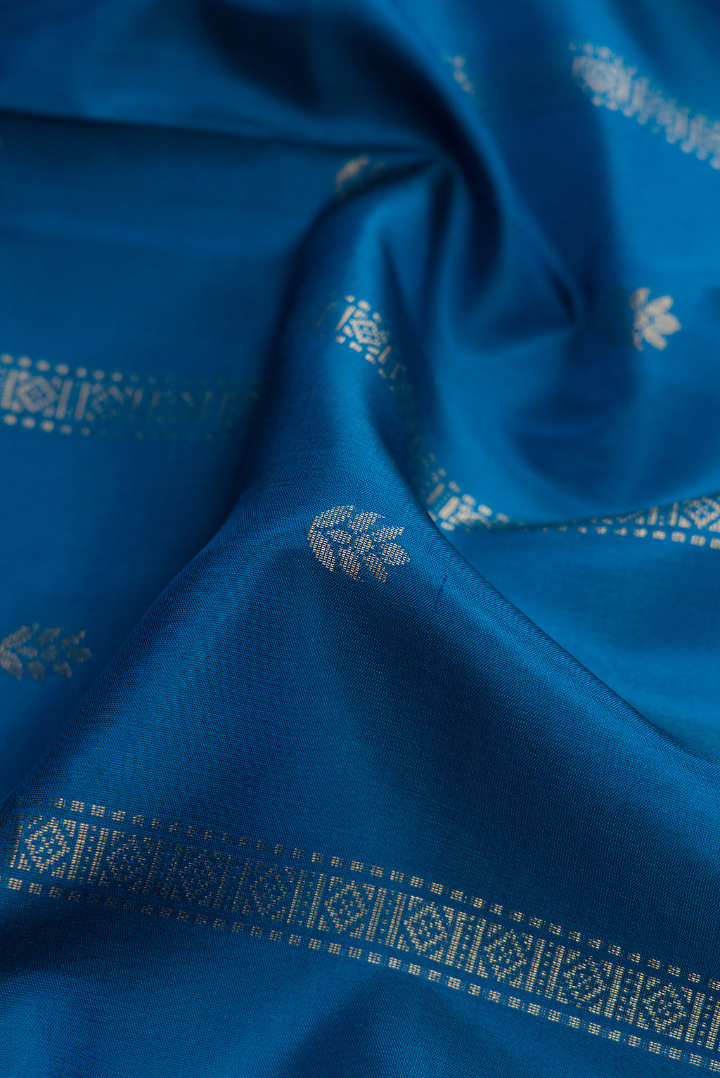 Close up of Peacock Blue Dual Tone Soft Silk Saree with Zari Butta on the body and Zari Border.  displaying folds