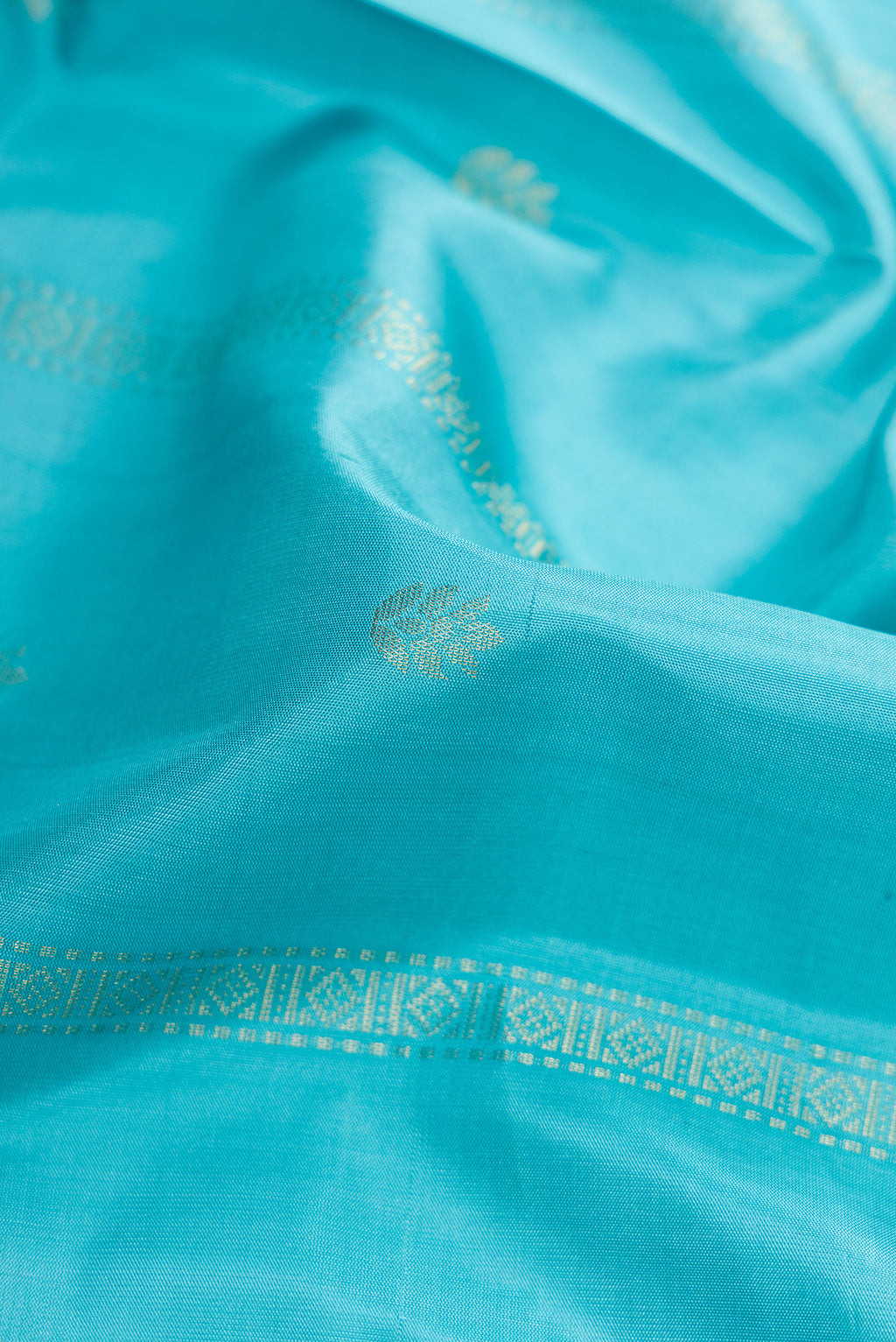 Close up of Sky Blue Dual Tone Soft Silk Saree with Zari Butta on the body and Zari Border.  displaying folds