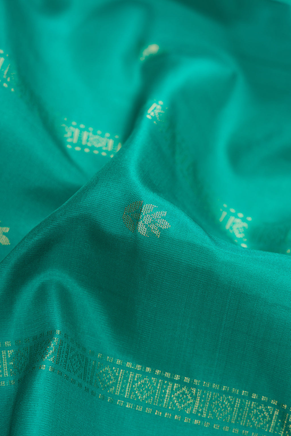 Close up of Green Dual Tone Soft Silk Saree with Zari Butta on the body and Zari Border.  displaying folds