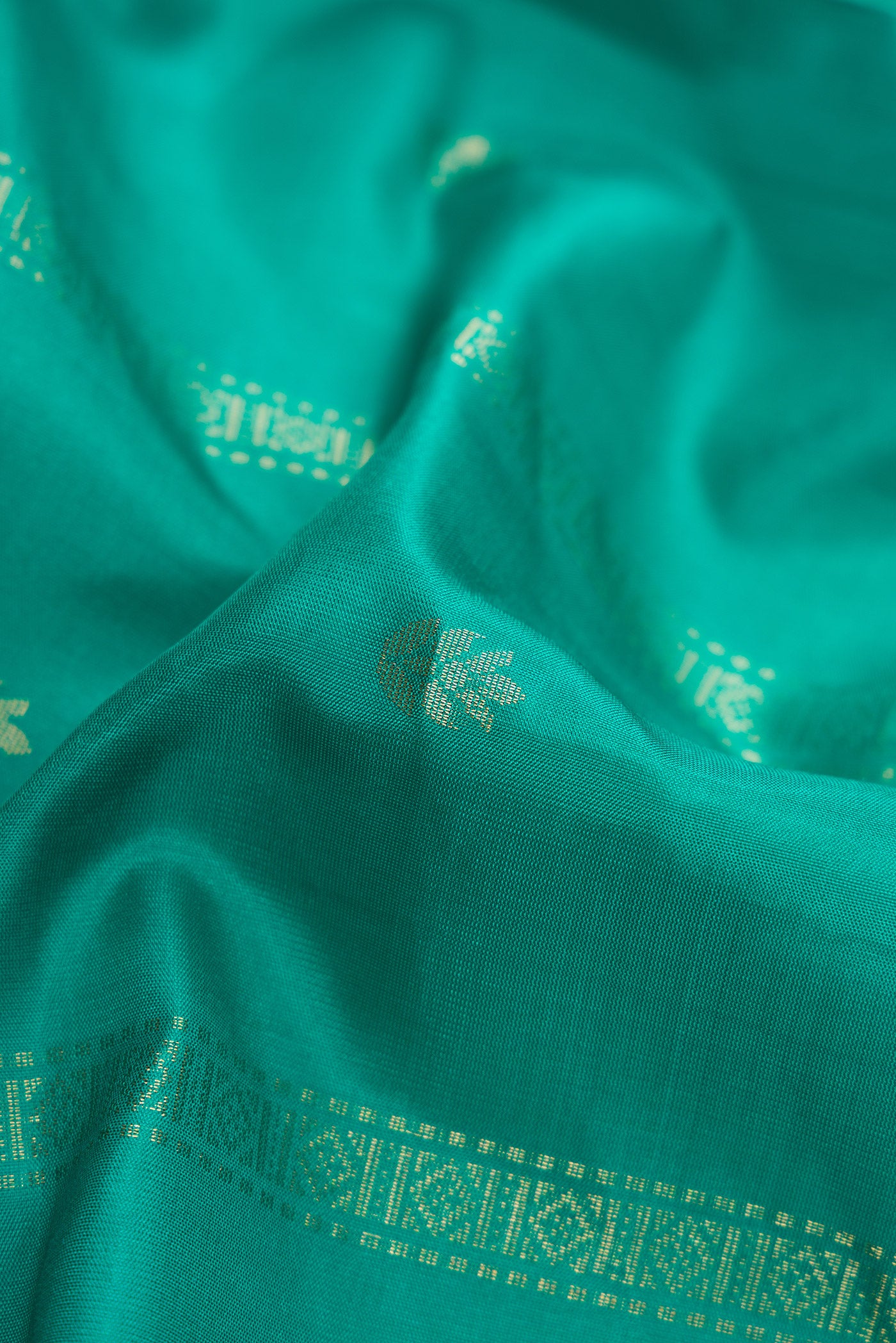 Close up of Green Dual Tone Soft Silk Saree with Zari Butta on the body and Zari Border.  displaying folds