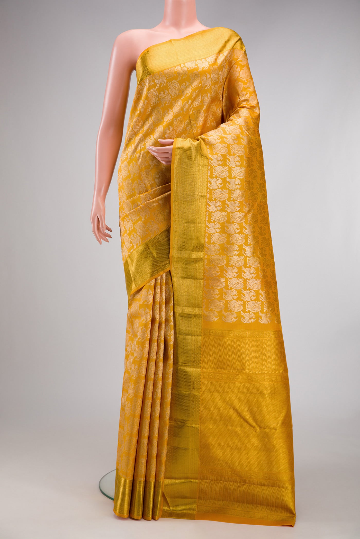 Mustard Kanchipuram Silk Saree with Zari Brocade on the body and Zari Border.  displayed on a mannequin