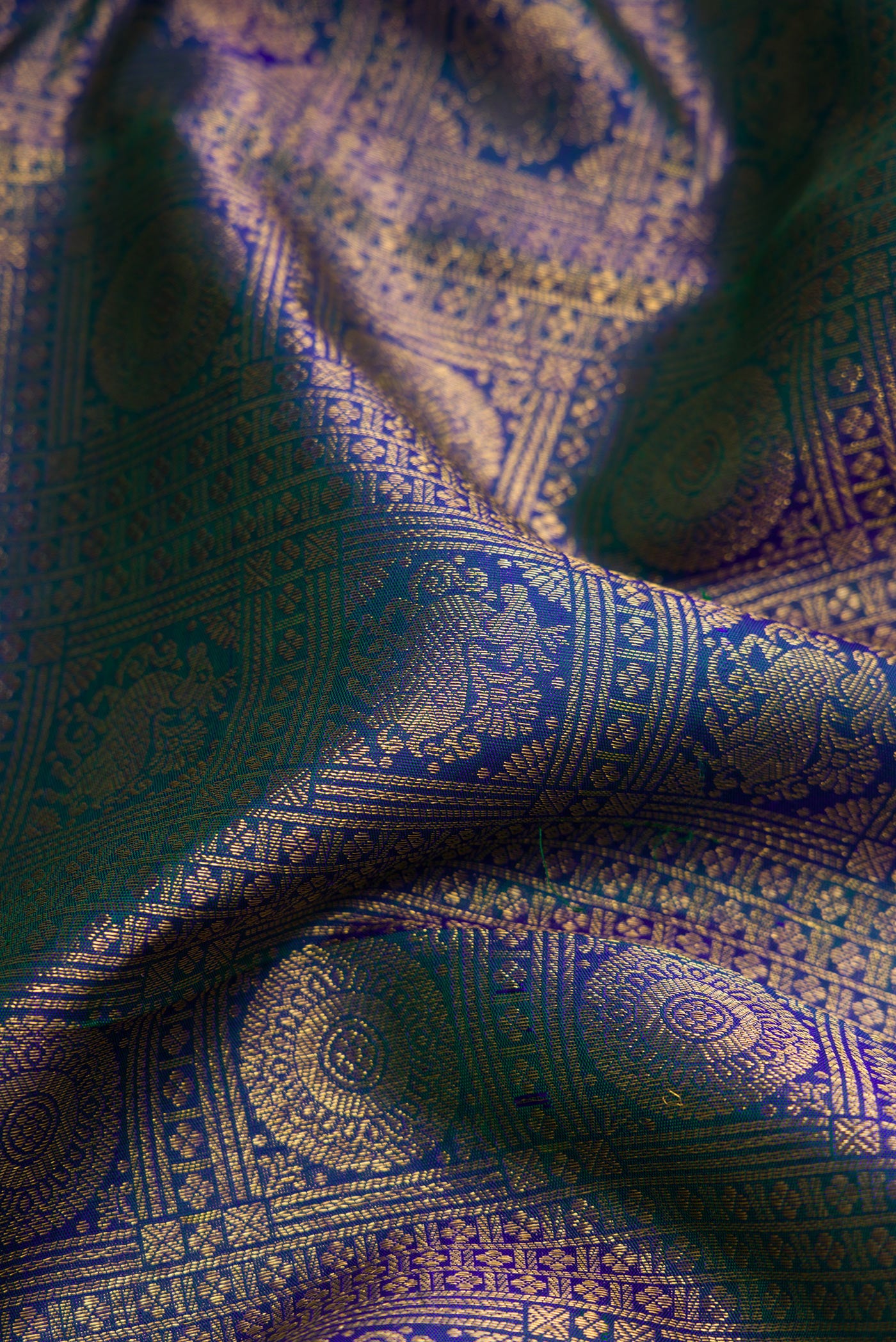 Close up of Peacock Blue Dual Tone Kanchipuram Silk Saree with Zari Brocade on the body and Zari Border.  displaying folds