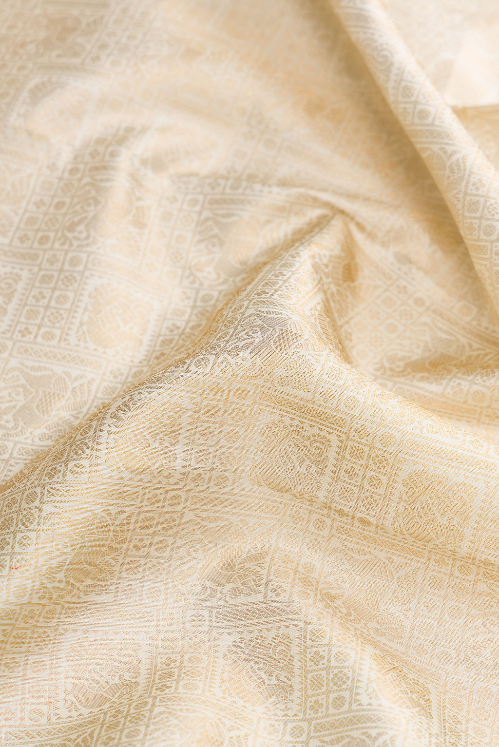 Close up of Off White Dual Tone Kanchipuram Silk Saree with Zari Brocade on the body and Zari Border.  displaying folds