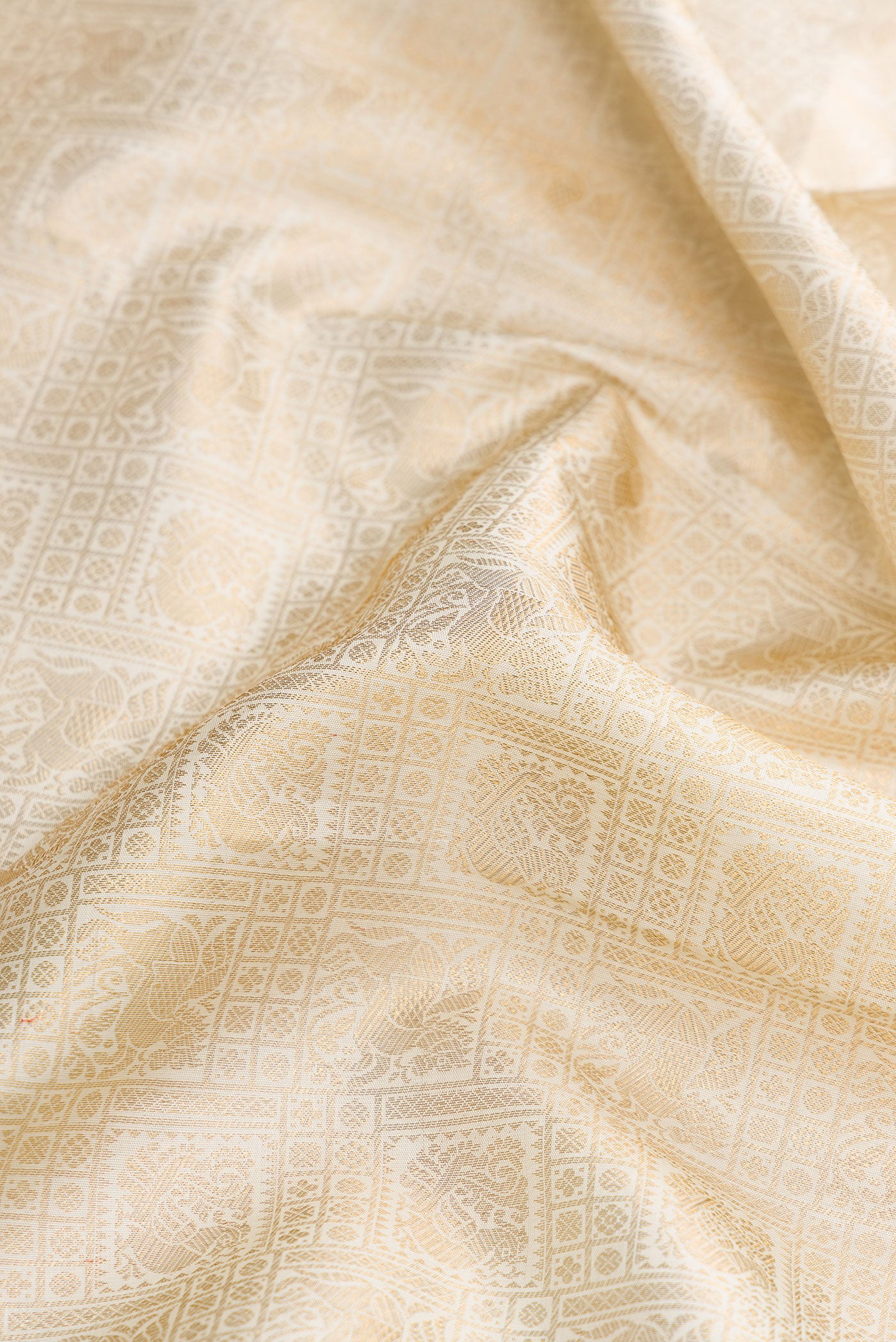 Close up of Off White Dual Tone Kanchipuram Silk Saree with Zari Brocade on the body and Zari Border.  displaying folds