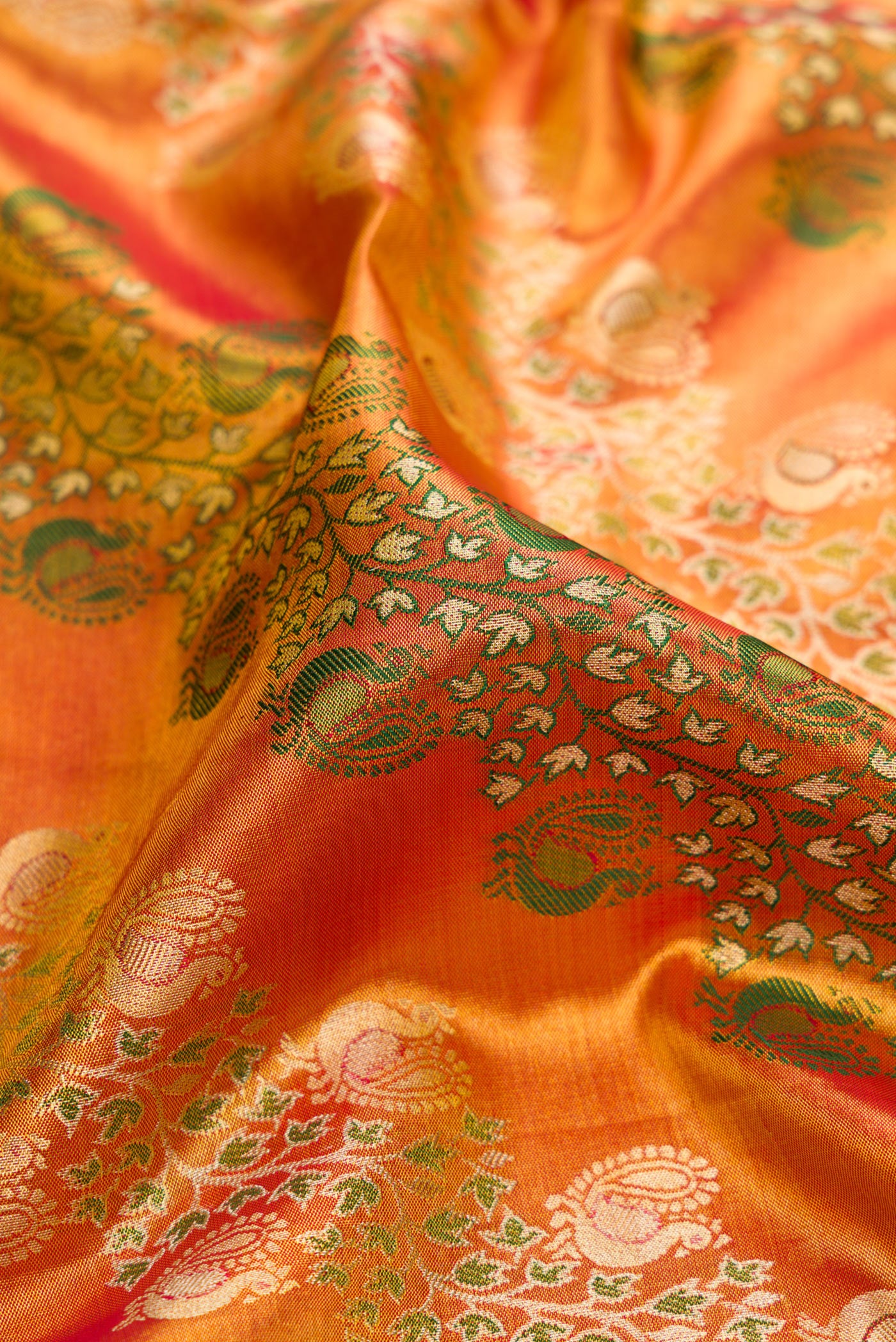 Close up of Golden Peach Dual Tone Kanjivaram Tissue Silk Saree with Zari Brocade on the body and Zari Border.  displaying folds