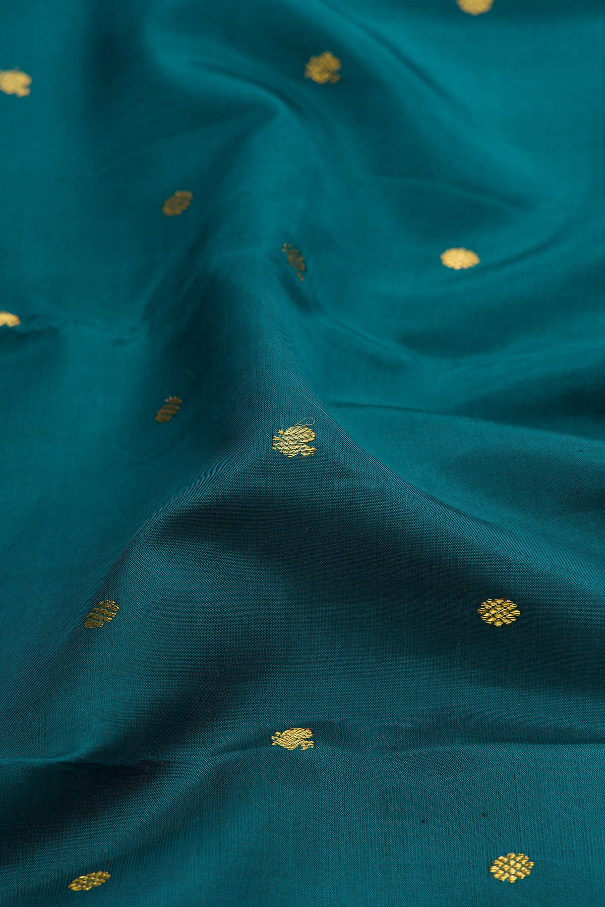 Close up of Peacock Blue Kanjivaram Silk Saree with Zari Butta on the body and Zari Border.  displaying folds