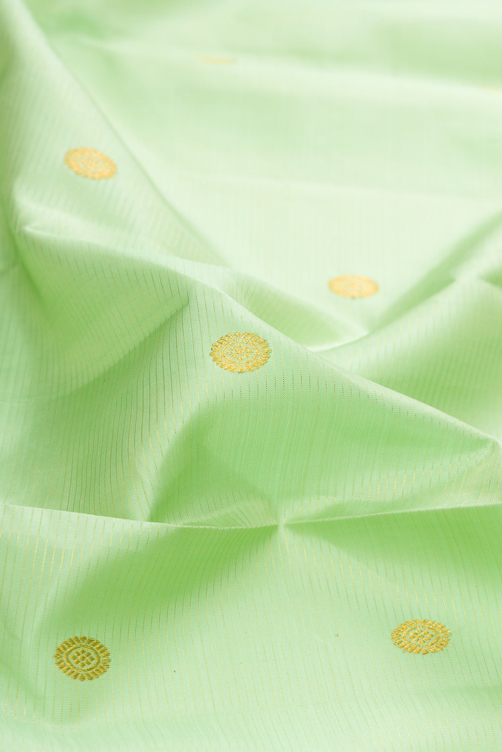 Close up of Pista Green Kanchipuram Silk Saree with Zari Butta on the body and Zari Border.  displaying folds