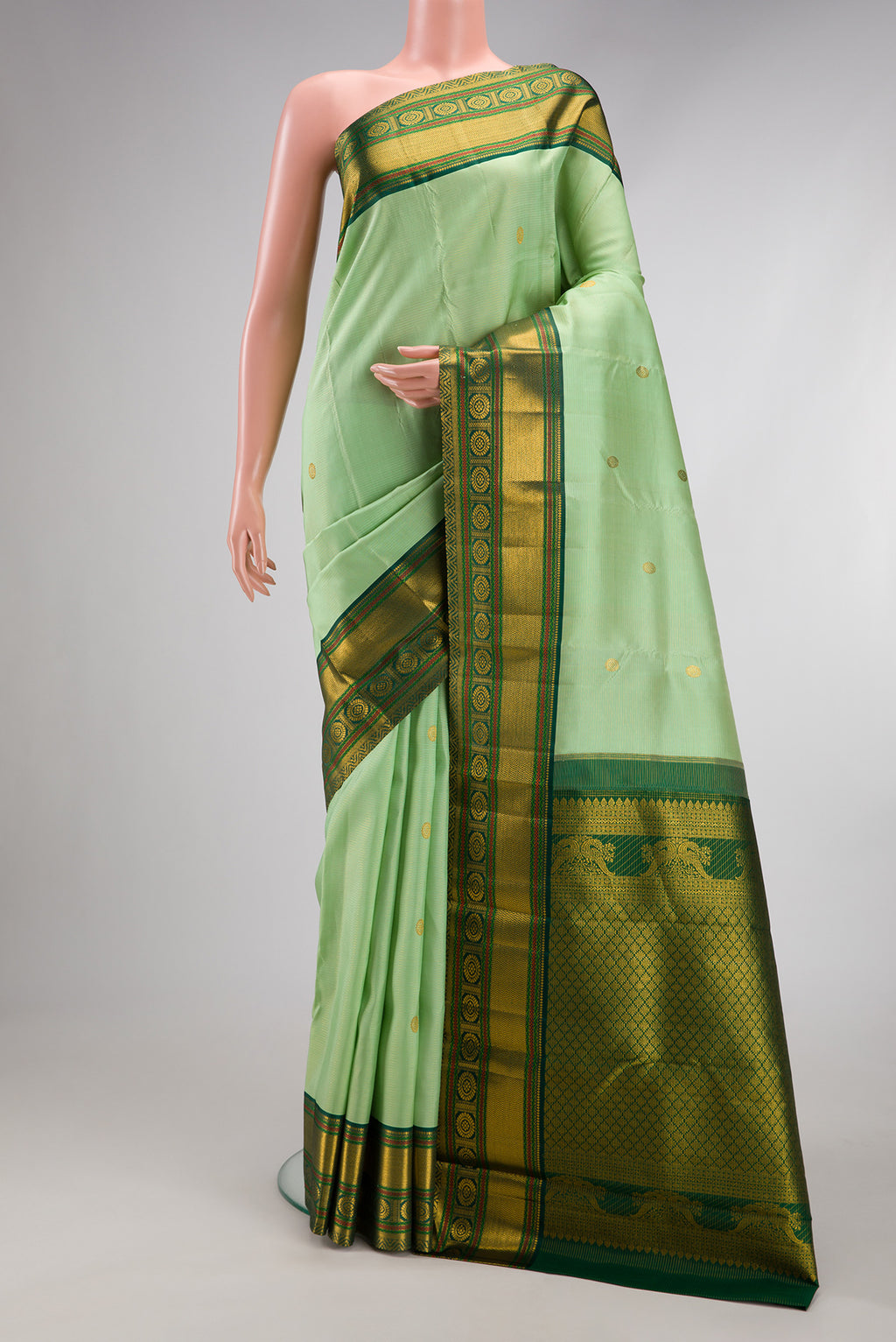 Pista Green Kanchipuram Silk Saree with Zari Butta on the body and Zari Border.  displayed on a mannequin