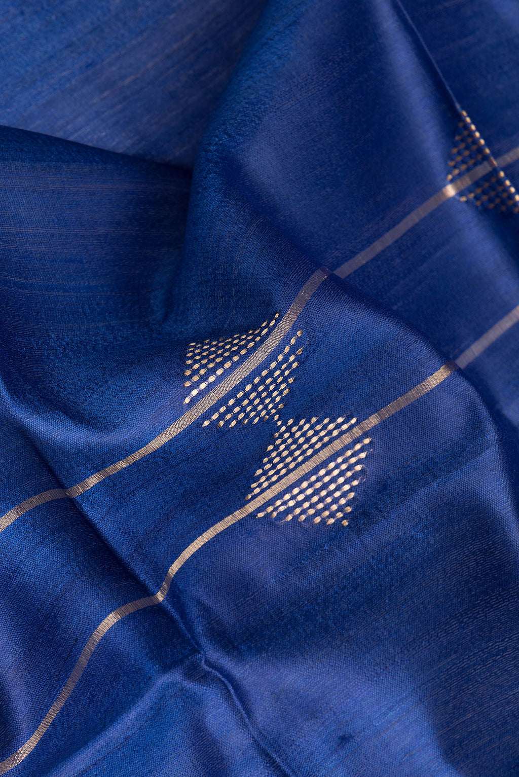 Close up of Royal Blue Tussar Silk Saree with Thread Butta on the body and Zari Border.  displaying folds
