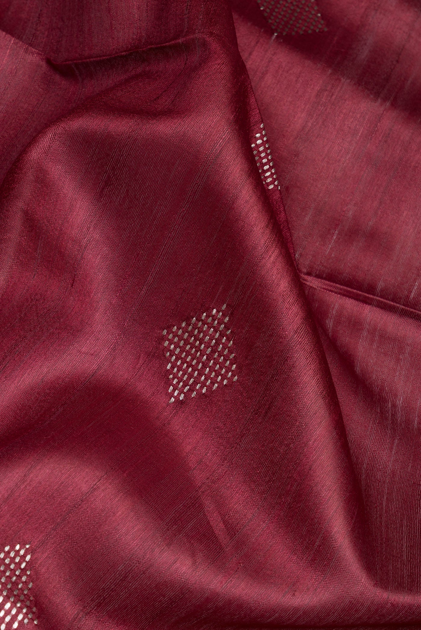 Close up of Maroon Tussar Silk Saree with Thread Butta on the body and Zari Border.  displaying folds