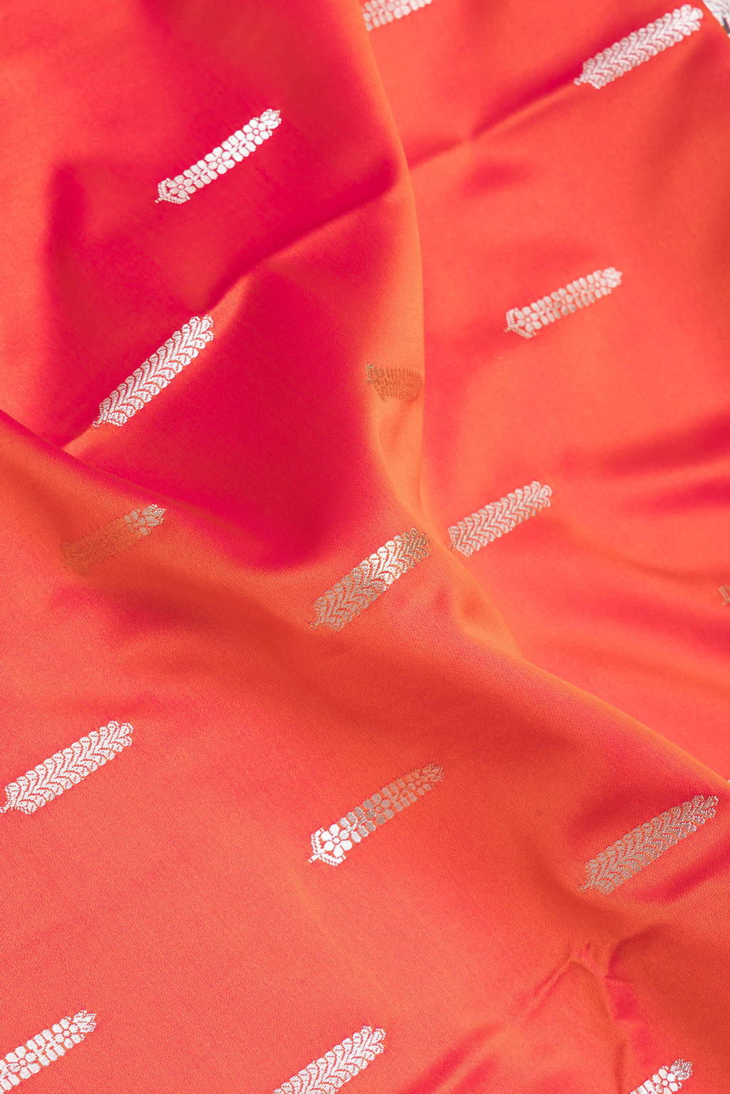 Close up of Orange Blended Banarasi Silk Saree with Zari Butta on the body and Zari Border.  displaying folds