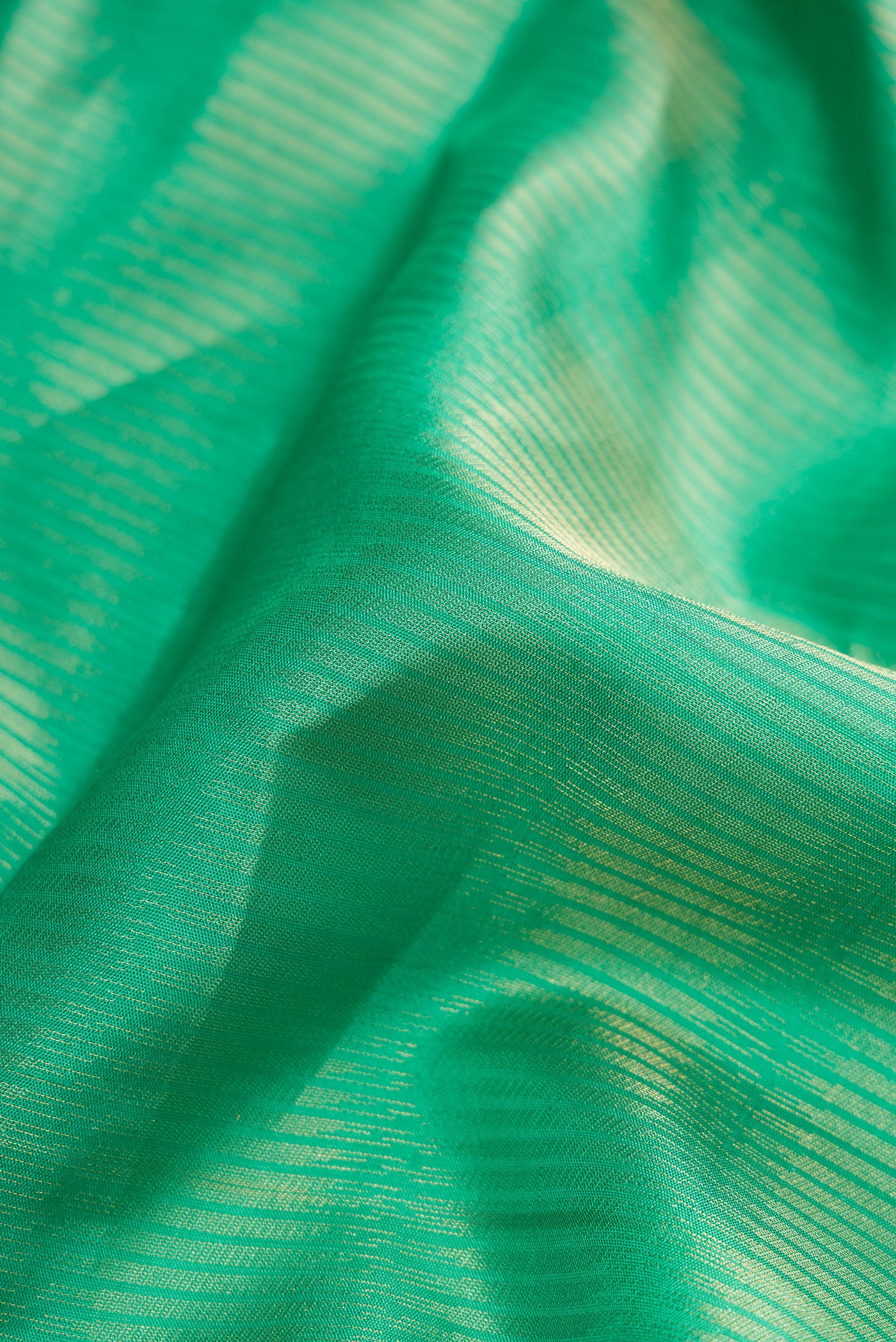 Close up of Green Dual Tone Soft Silk Saree with Zari Butta on the body and Zari Border.  displaying folds