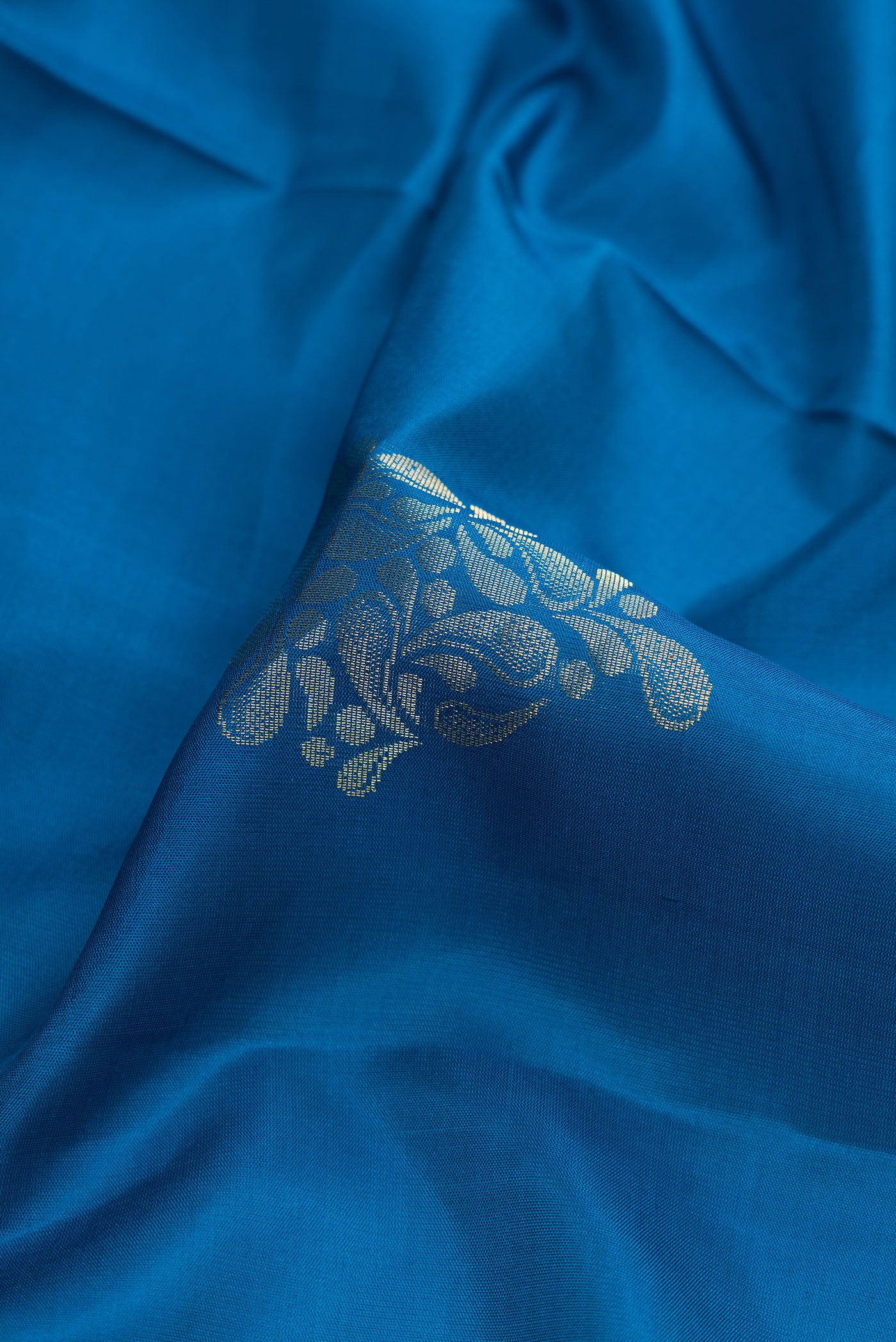 Close up of Peacock Blue Dual Tone Soft Silk Saree with Zari Butta on the body and Zari Border.  displaying folds