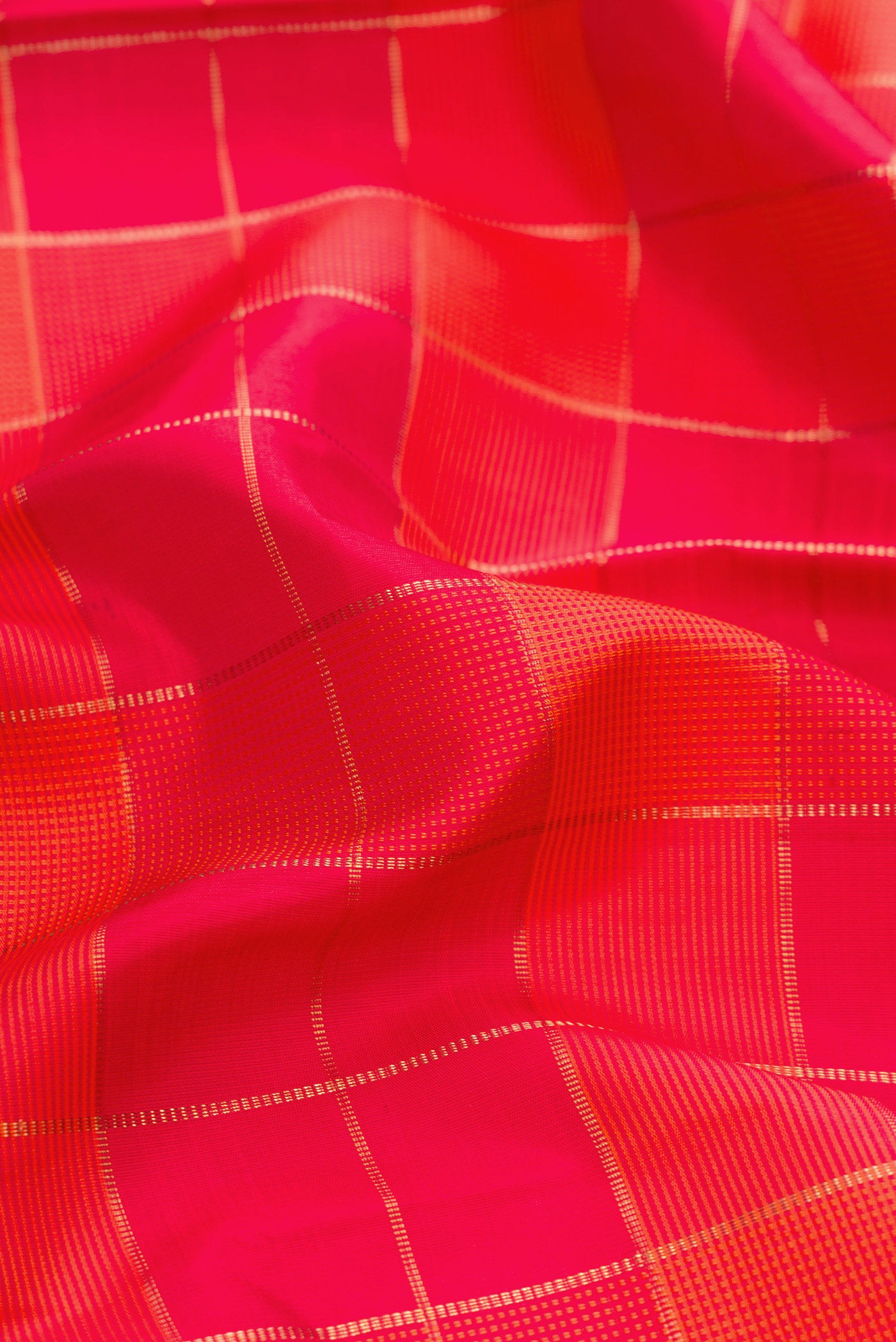 Close up of Pure Silk Pure Zari Orange and Dark Pink Color Kanchipuram Saree with Checked design on the body and Plain Border.  displaying folds